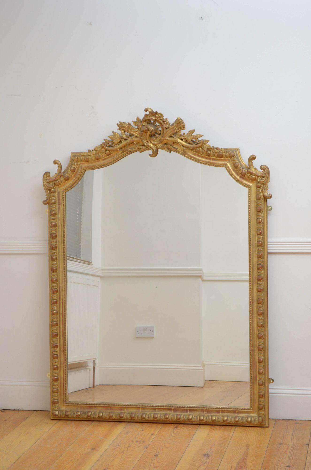 J014 Fine French gilded wall mirror, having original glass with minor imperfection in carved, beaded and gilded frame with finely carved centre crest flanked by leafy scrolls. This antique mirror retains original gilt and is in home ready condition.