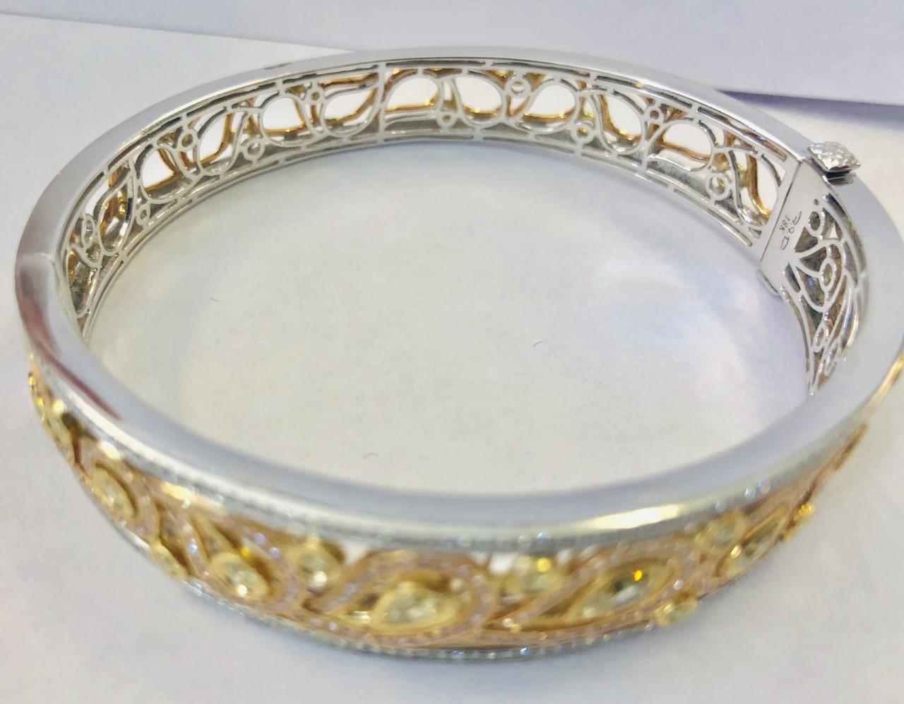 18KT Gold, Yellow Diamond Bangle-Bracelet 
Open work design and set at the front with three pear shaped yellow diamonds, weighing approximately 0.87 cts, and 178 round cut diamonds weighing approximately 0.66 cts

Measuring 2.4 x 2 in, weighing