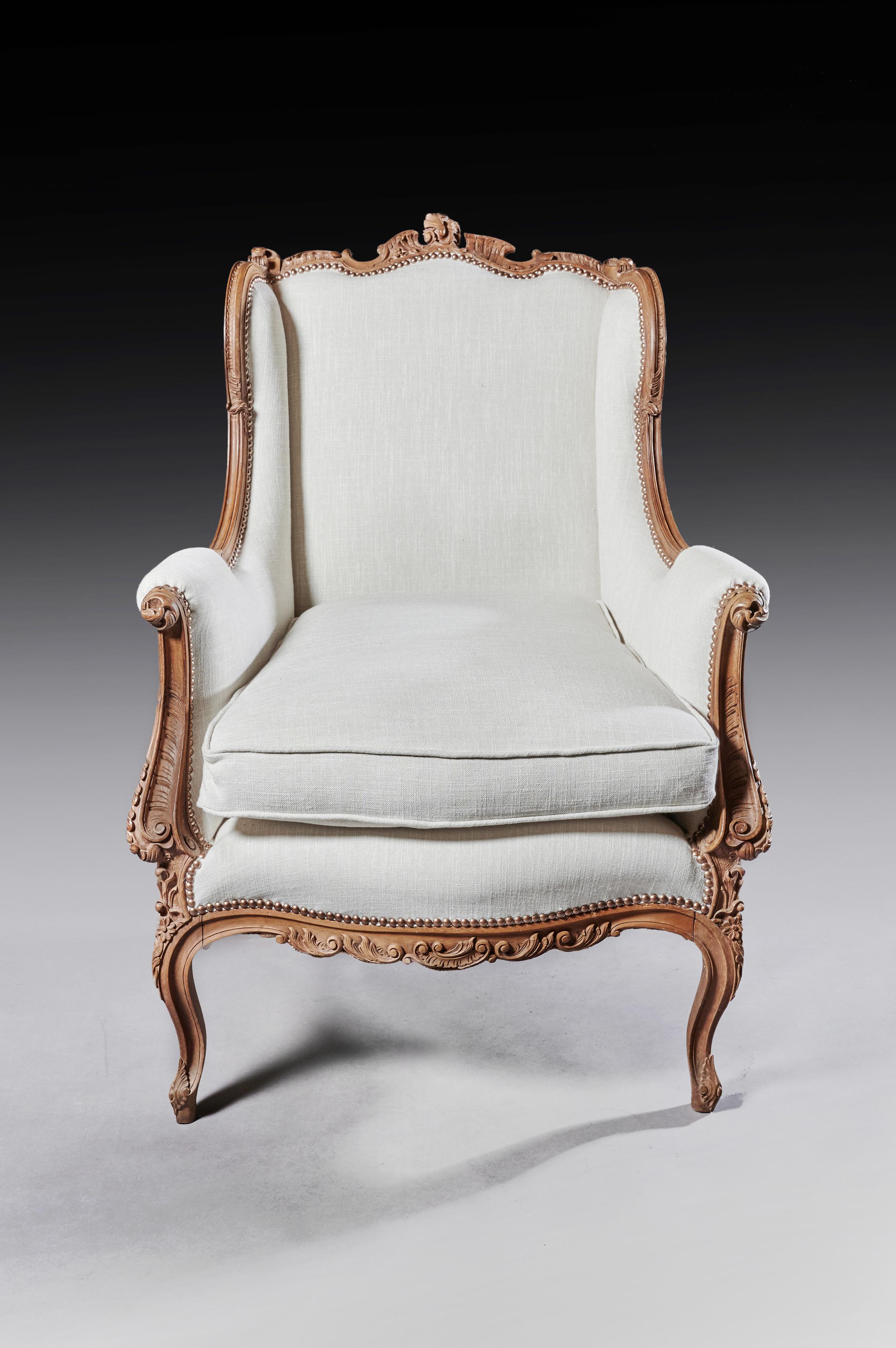 A finely carved 19th century French Louis XV style wingback armchair upholstered in linen.

French, circa 1870.

A decorative and well carved solid walnut wing back armchair having a shaped back with winged show wood sides falling to scrolled