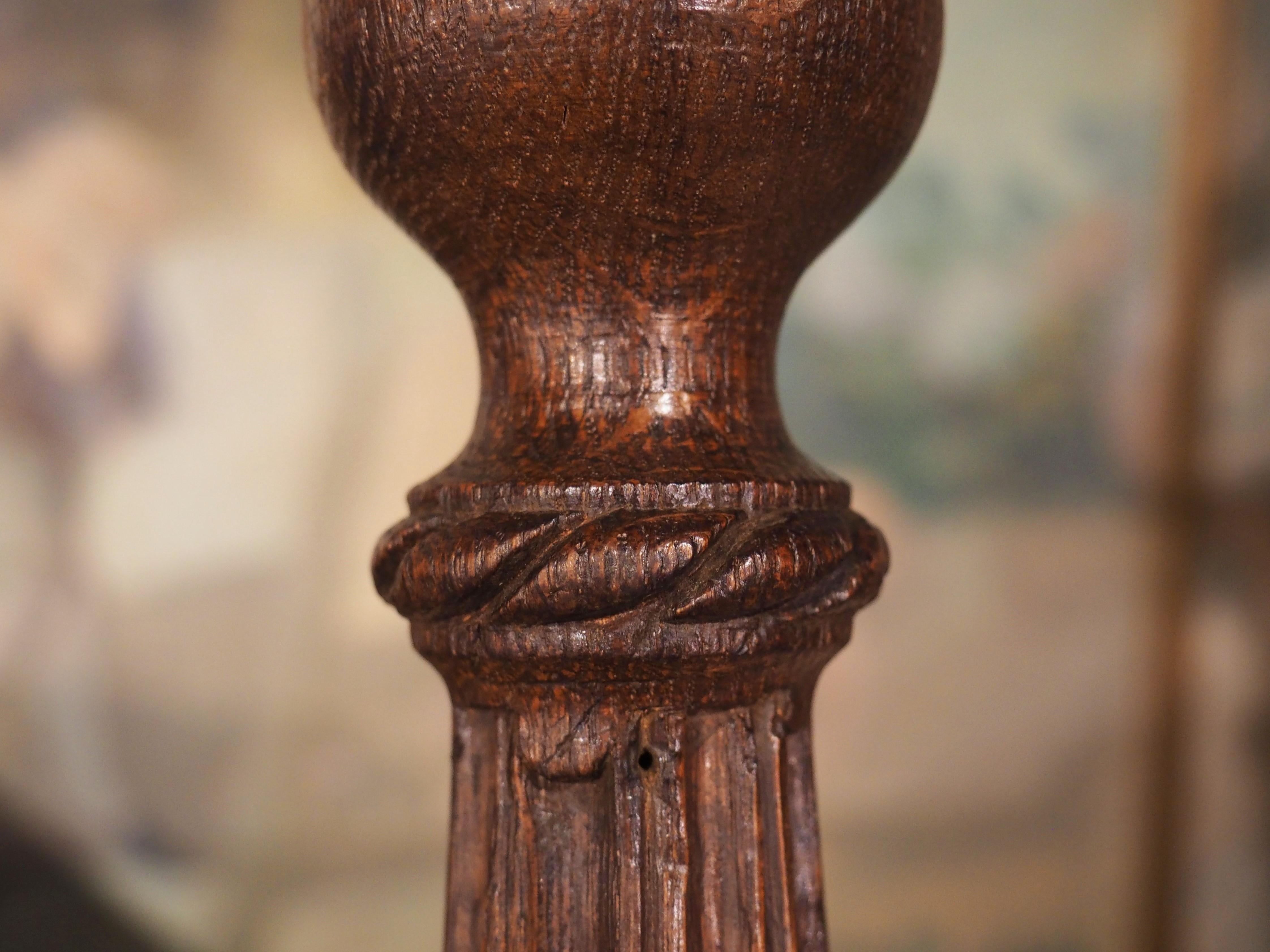 With its finely carved foliate motifs, this antique candlestick has an equally impressive rich, deep brown color from an unmatched patina. hand carved from oak in France in the late 1700s, the elegant candlestick sits on top of a tripartite base