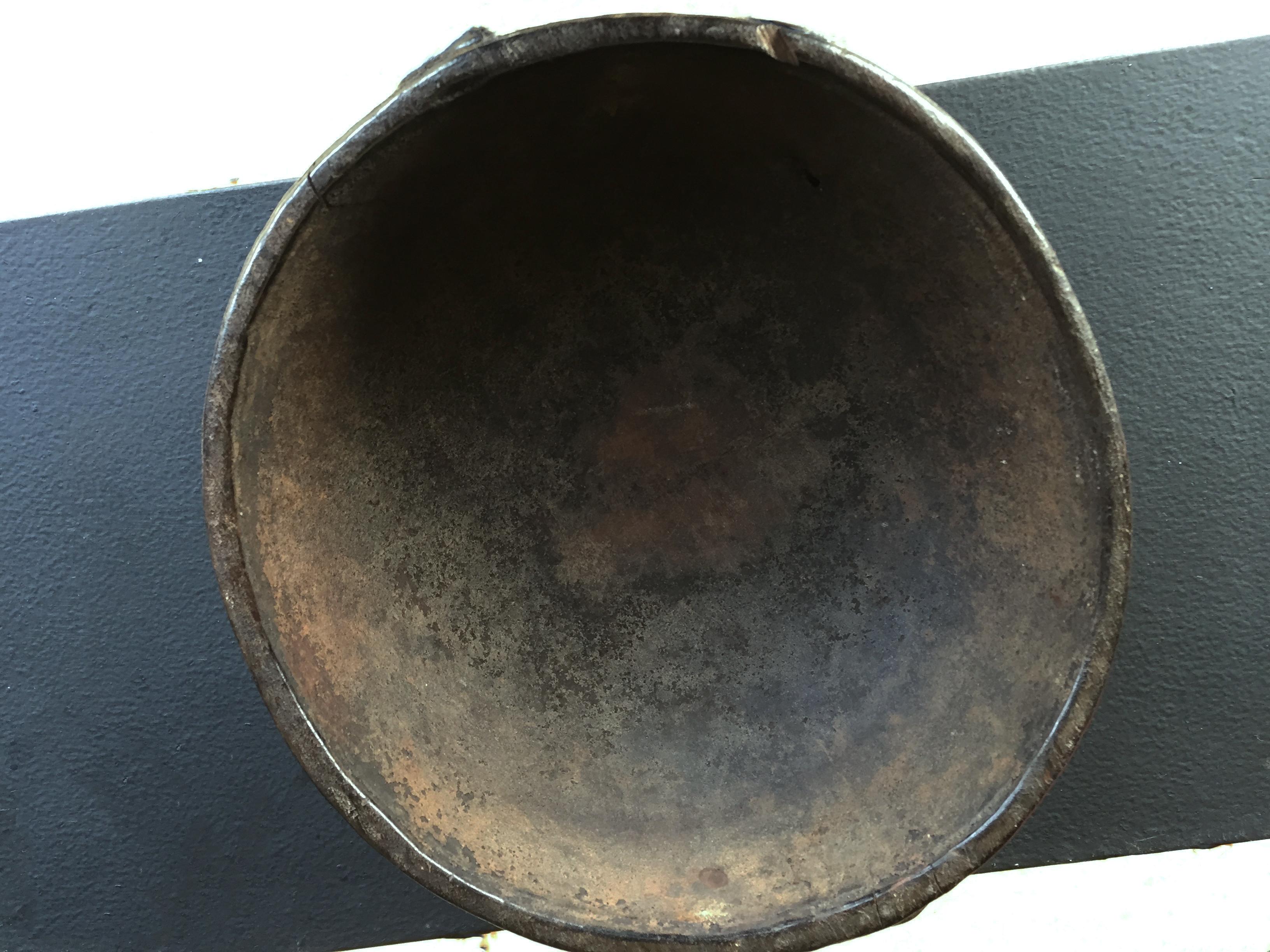Boiken bowl, shallow circular form, the underside carved in shallow relief with a star design,
stylised motifs within its border leading the two handles with notched edge and two lovely well worn faces on the edge , black patina, wear according to