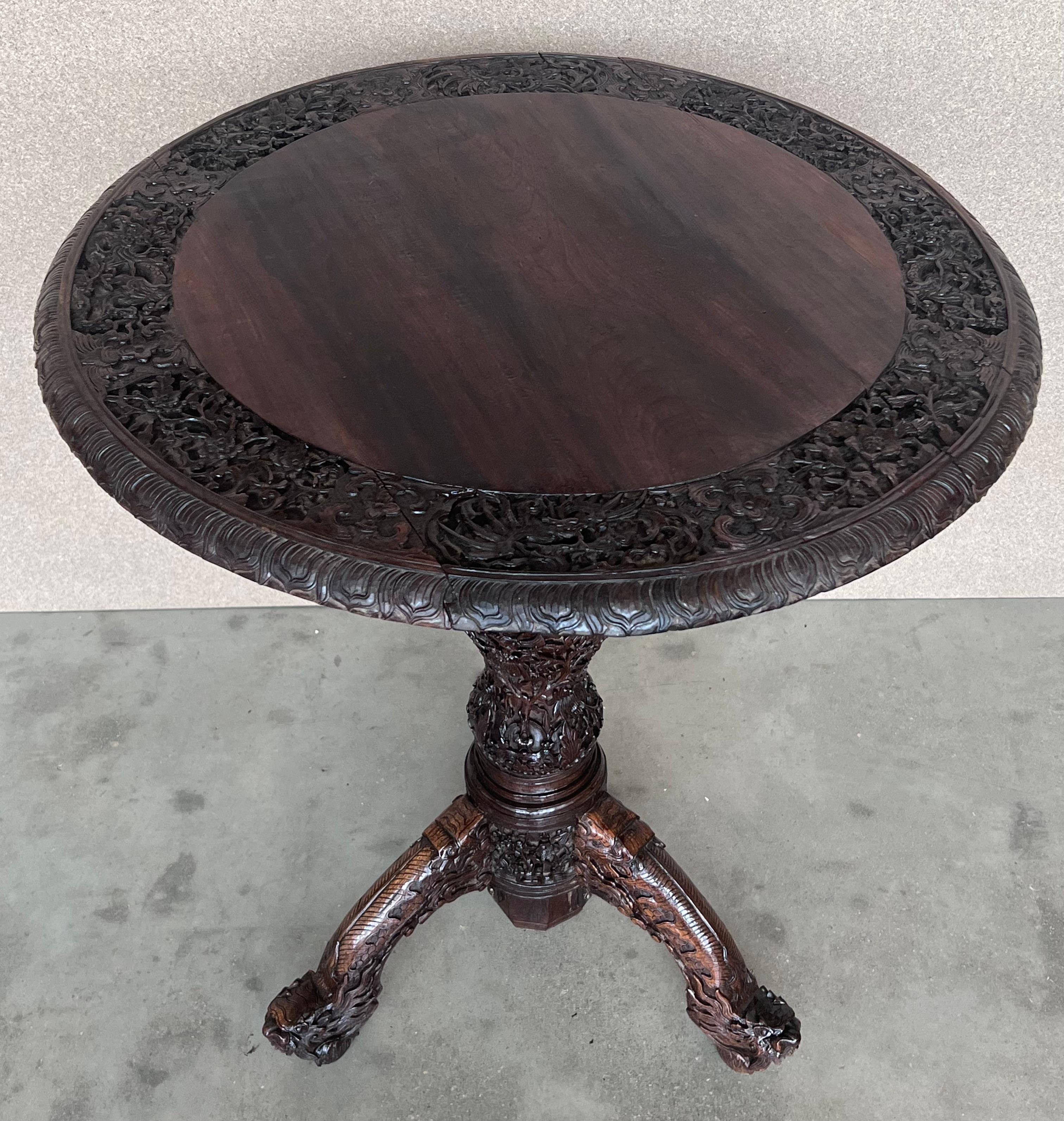 Magnifique table d'appoint circulaire en bois finement sculpté de l'époque coloniale britannique, originaire d'Inde ou de Coloni. Le plateau circulaire est orné d'une large bordure détaillée en bas-relief représentant un lion et un serpent au milieu