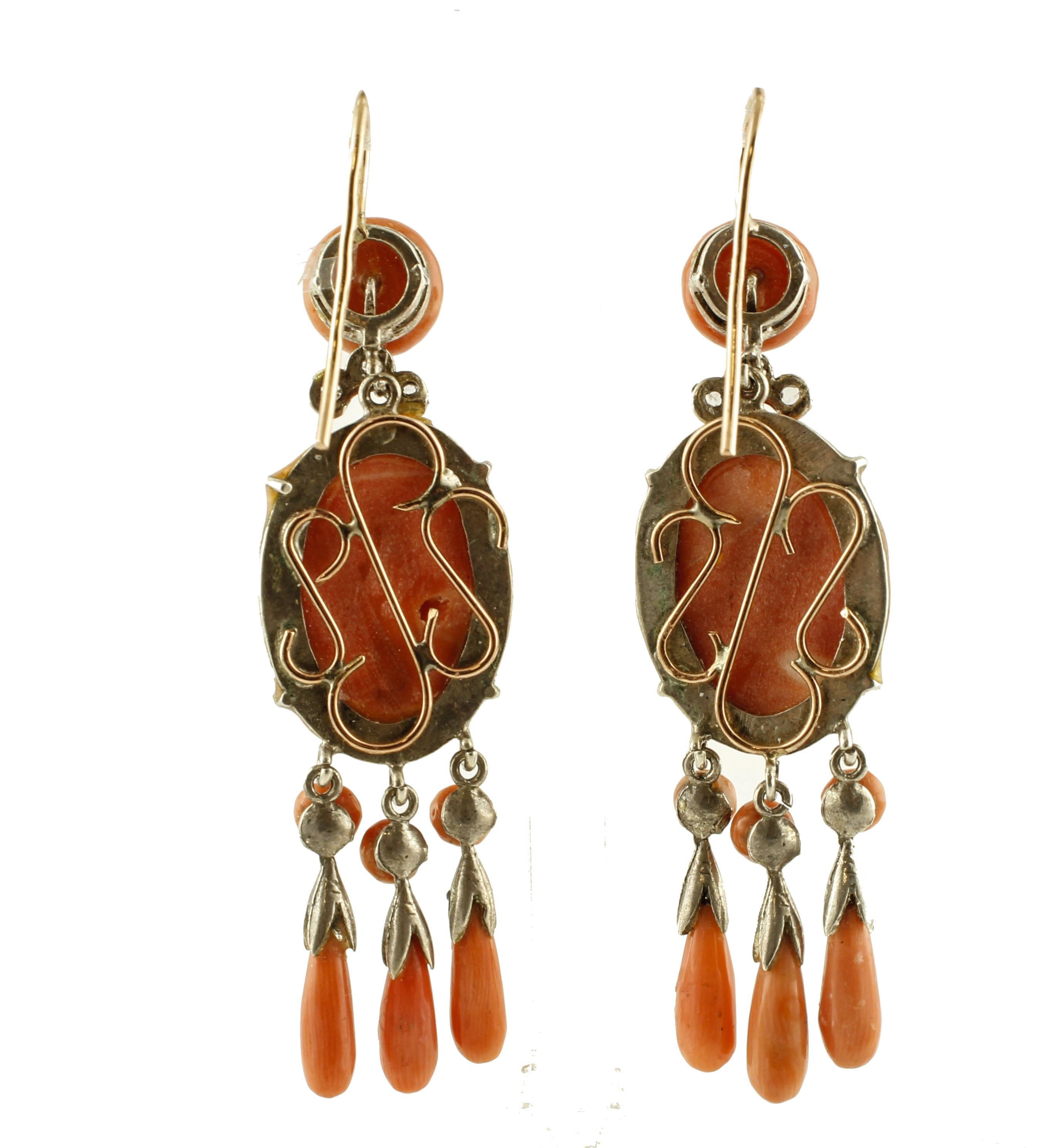 Marvelous dangle coral earrings in 9k rose gold and silver structure mounted with a central finely carved elatius coral representing male motifs and small drops of coral which dangle below it. 
These earrings are totally handmade according to the