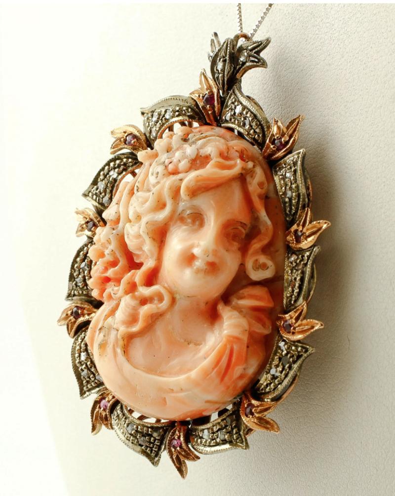 This gorgeous retro pendant/brooch is mounted with 14.80 gr of big pink coral finely carved with lady motif, framed by rose gold and silver structure studded with diamonds and rubies.
The origin of this pendant/brooch dates back to the 1850'.
The