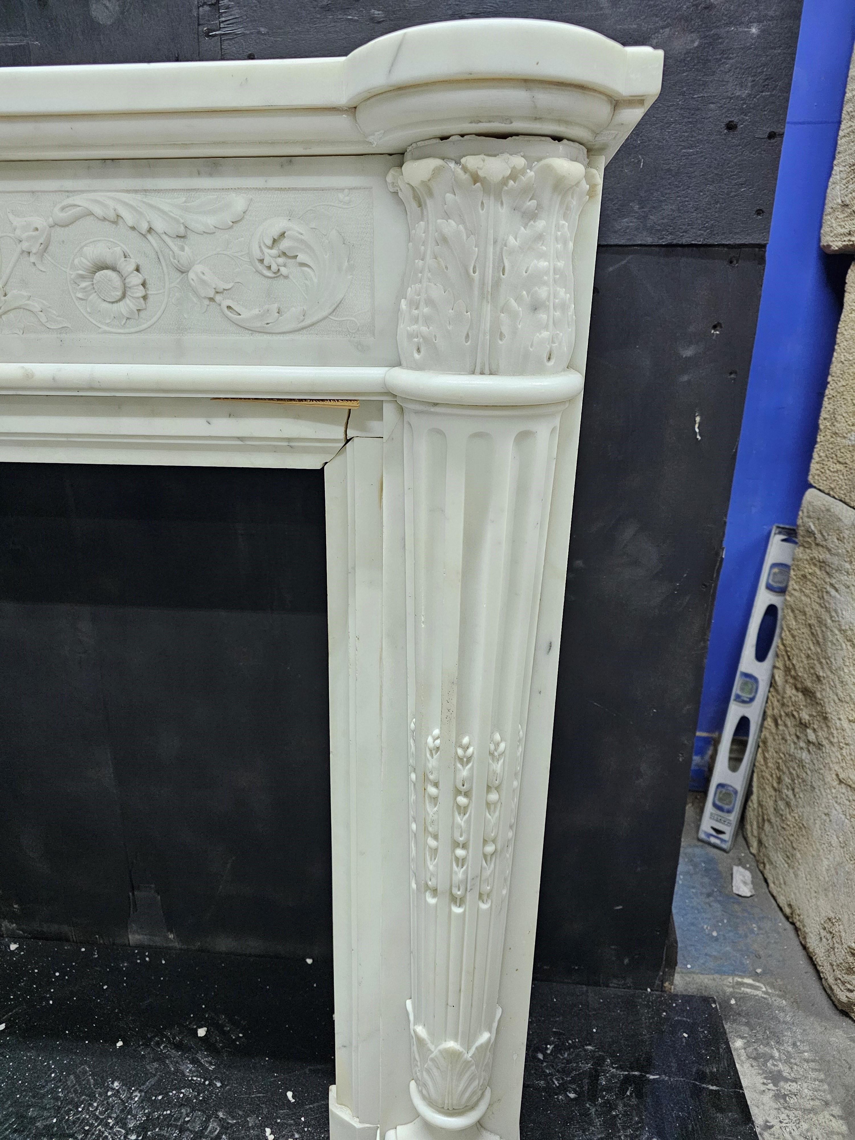 Finely carved early 19th c French chimneypiece in statuary marble with engaged stop fluted half round columns terminating beneath acanthus carved capitals, the frieze with delicately carved low relief foliate arabesques against a hammered