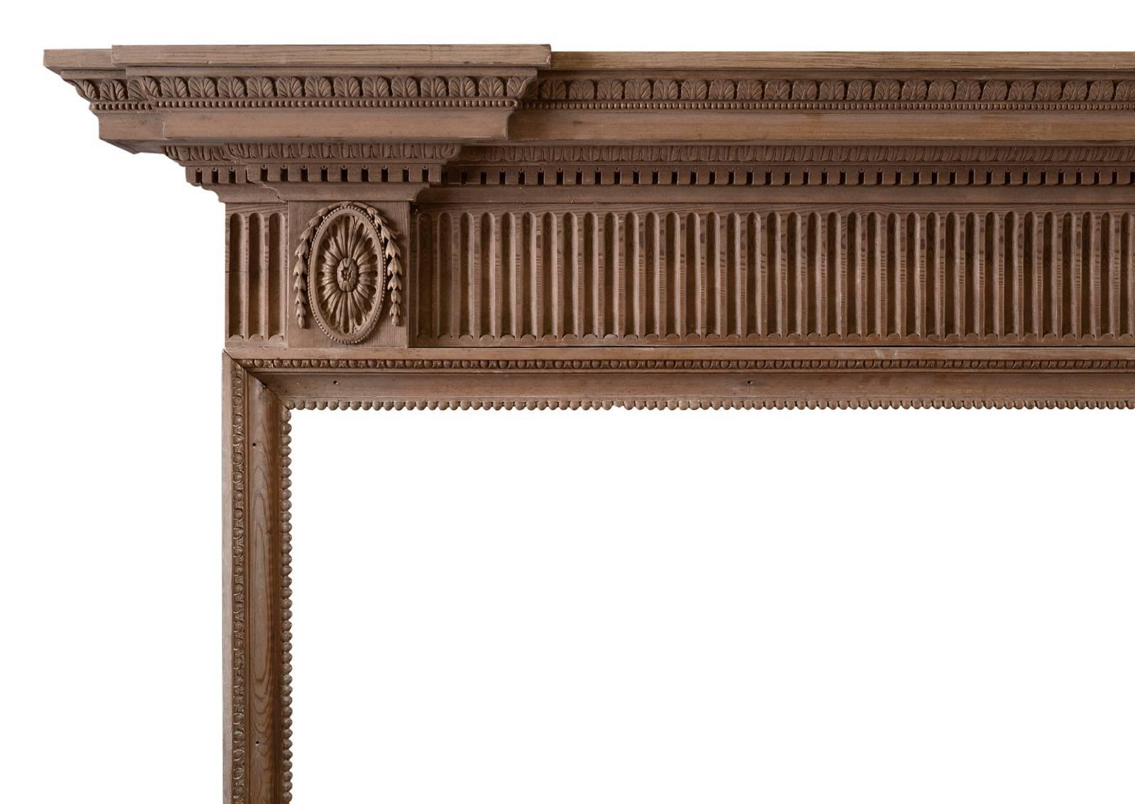 A delicate Georgian style fireplace. The fluted frieze with oval paterae and husks to end blocks, the shelf with stiff waterleaf mouldings, beading and dentils. Photo’d prior to restoration – a minor repair required to inside of leg, included in