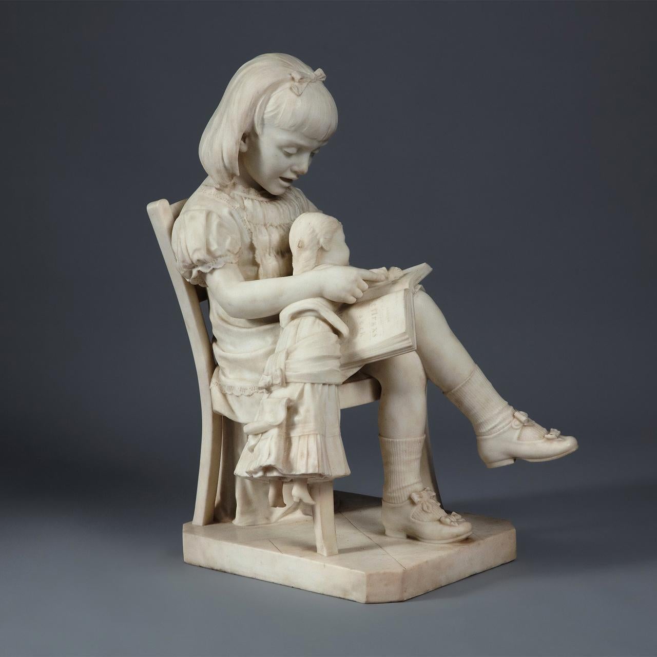 A signed finely carved Italian Carrara marble sculpture of a girl reading to her doll siting on a chair.

Title: La Lezione Di Lettura
Artist: L. Tolducci (19th century); Italian School
Date: 19th century
Dimension: 31 in. x 20 in. x 25 in.