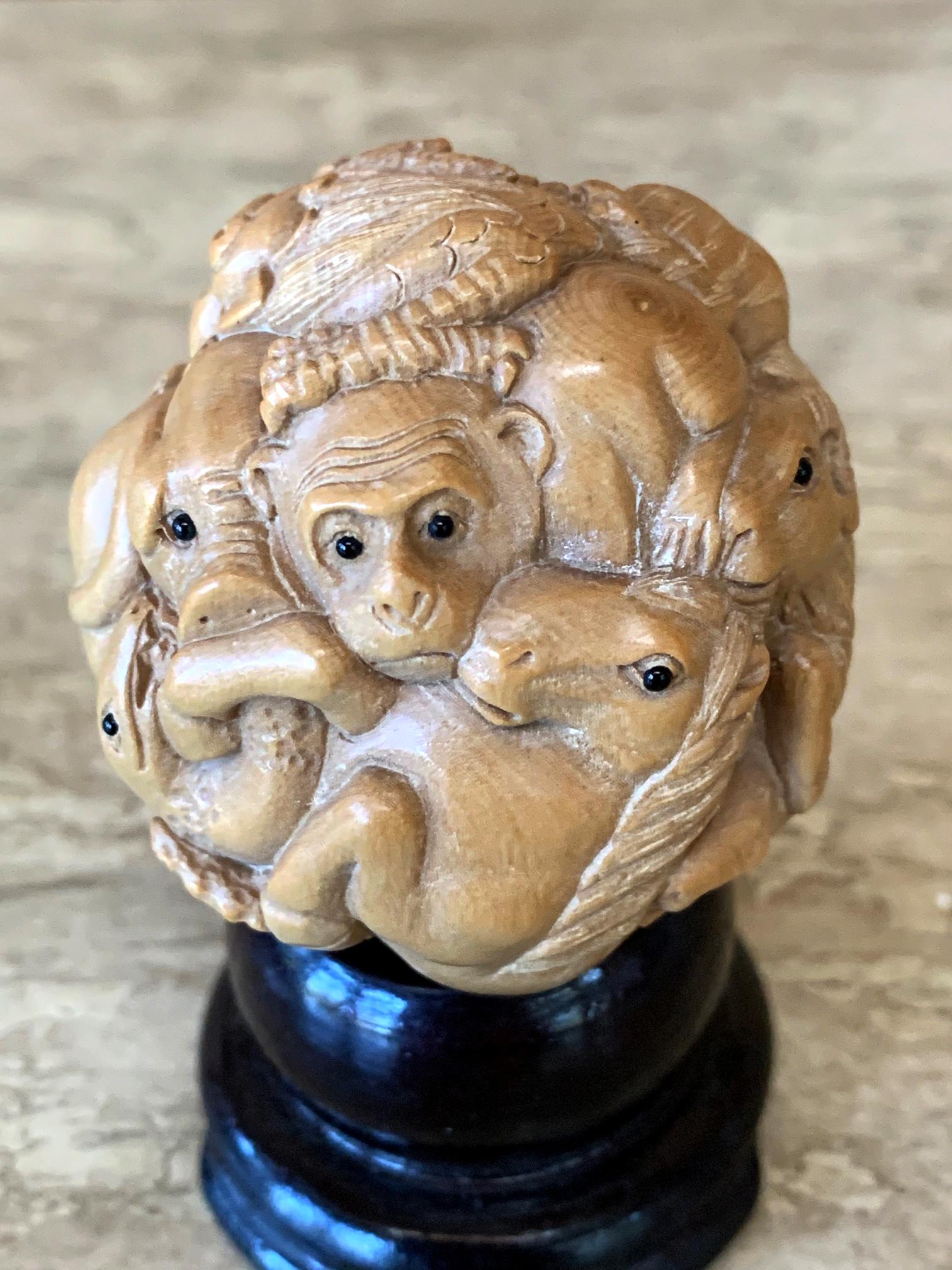 An antique Okimono (Japanese means artsy display ornament object) displayed on a small custom wood stand from Meiji Period circa early 2oth century. The ball form was finely carved out of a light colored wood. It depicts twelve zodiac animals