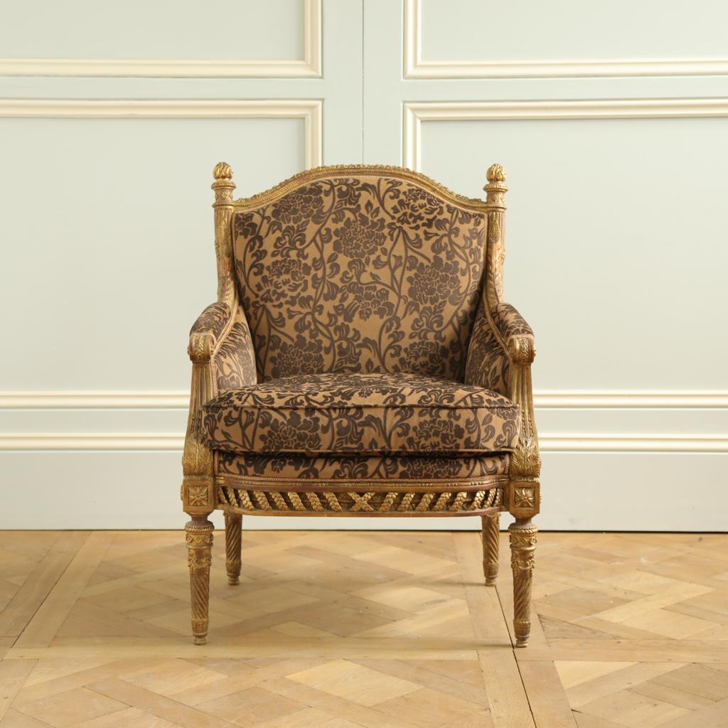 A Louis XVI style armchair featuring exquisitely fine carving from LML's most master carvers. The piece is a replication of originals, made to the highest standards and finished in a hand gilded patina which has been given an old gold, warmth and