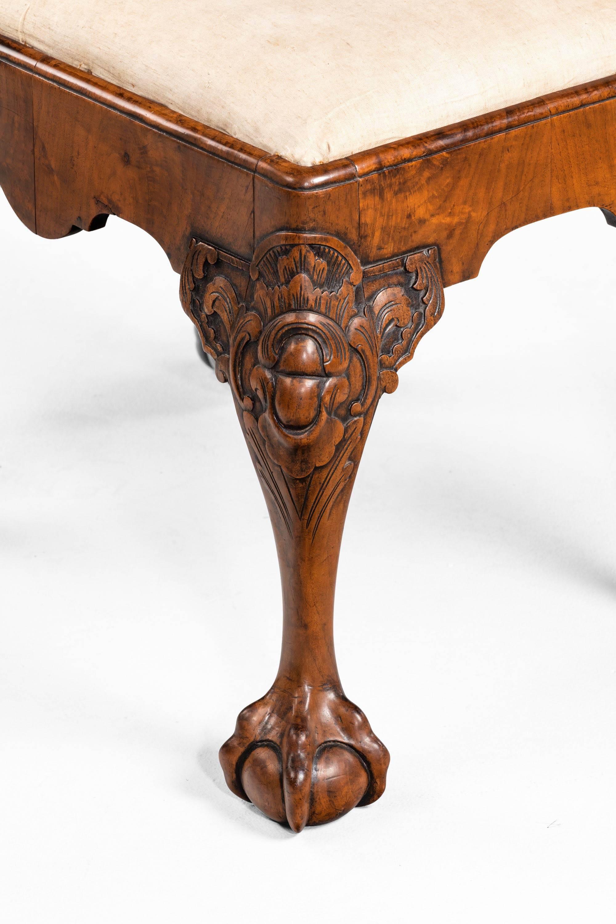 A finely carved walnut stool in mid-18th century style. With elaborately scrolled knees terminating in claw and ball feet. Lovely, faded, warm honey color.
      