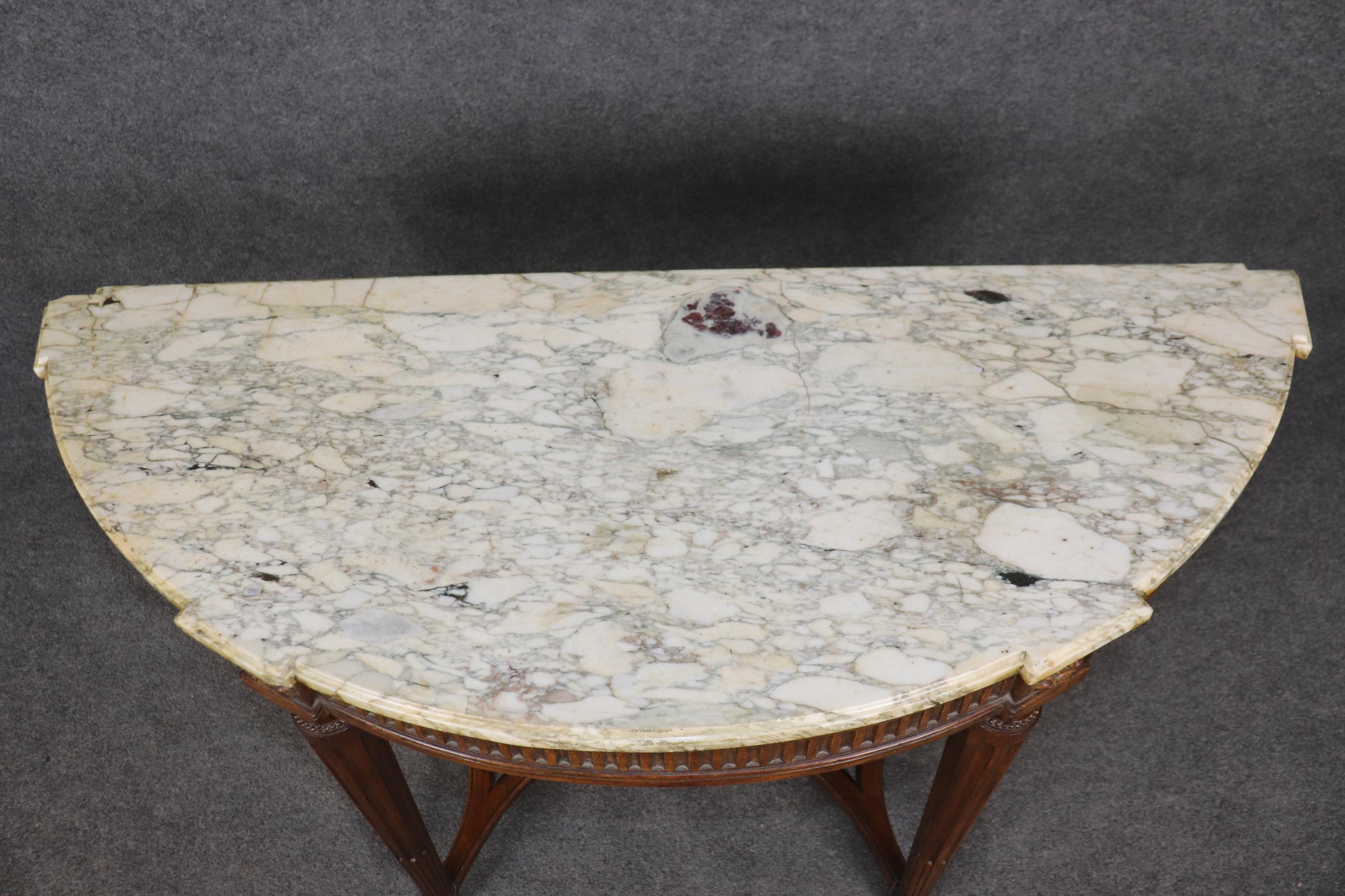 This is a fantastic and ultra-pure French Louis XVI designed French-made console table. The table is designed in the demilune style and features crisp, meticulously done carving and a gorgeous slab of French Breche D' Violette marble. The table is