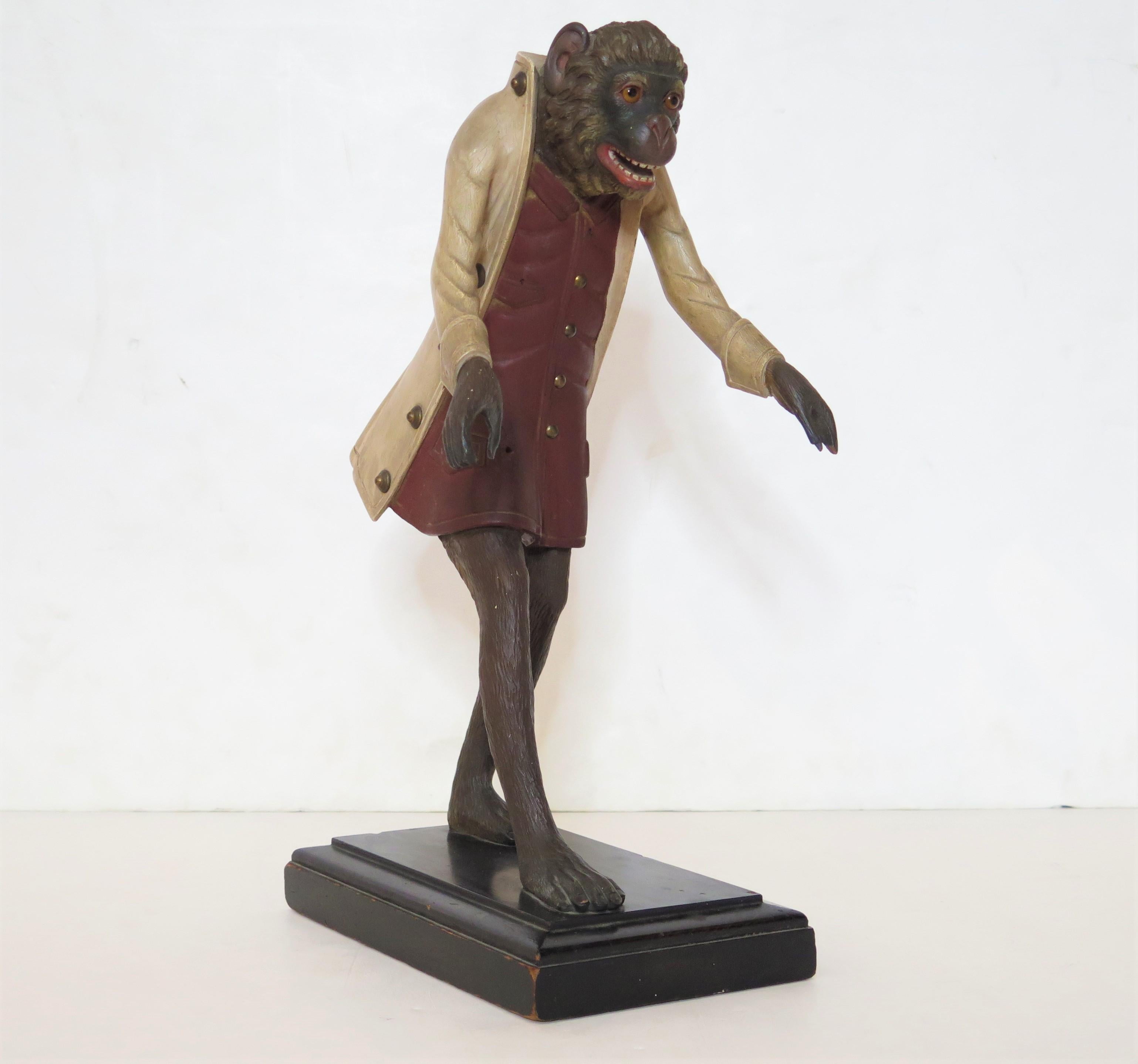 a finely carved wooden monkey butler / servant / footman figure on stand, glass eyes, open mouth with teeth, once held a tray in its outstretched arms / hands (missing / lost to time), top button missing from waistcoat, also missing a pocket watch