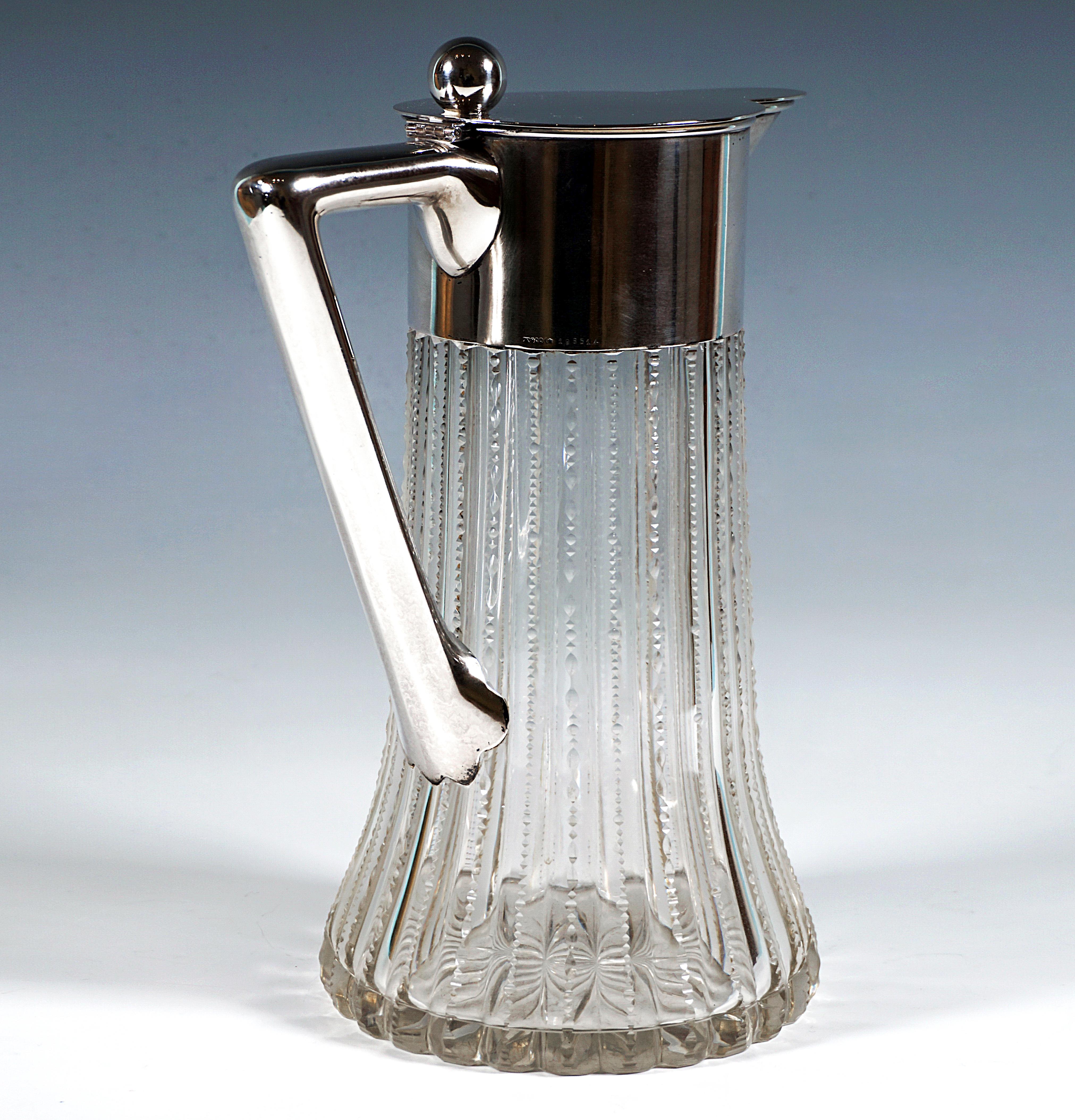 Elegant large carafe made of clear glass with a conical body, glass wall vertically cut with regular jagged facets on the outside, jagged ridges rounded off by a delicate lenticular cut resembling pearl necklaces, cut bottom star, smooth silver