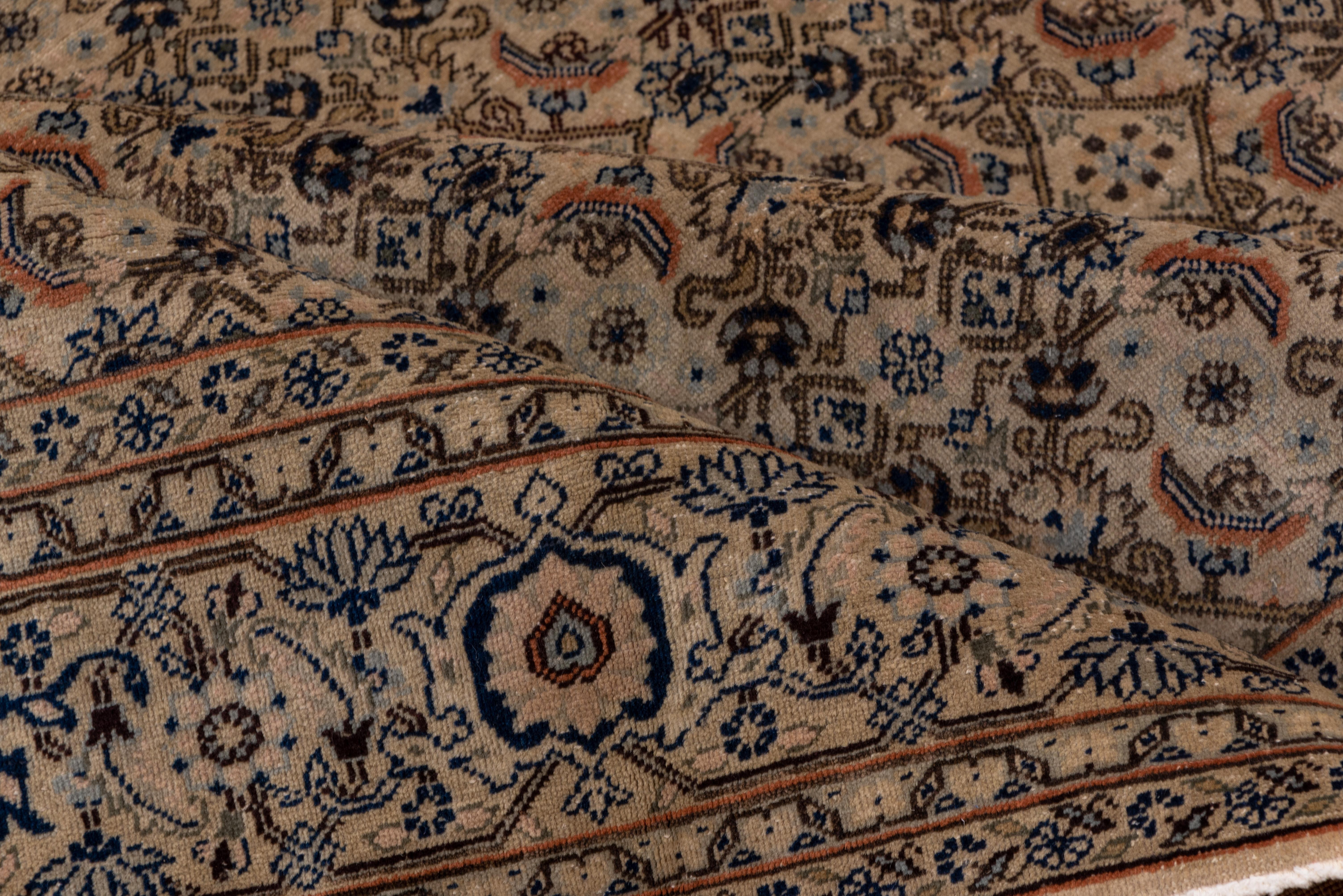 Carefully knotted in the Tabriz manner, this eastern Turkish town carpet shows a straw-sand field with an evenly executed allover Herati design of open diamonds, rosettes, broken leaves and rose palmettes. Cream main border with blue reversing open