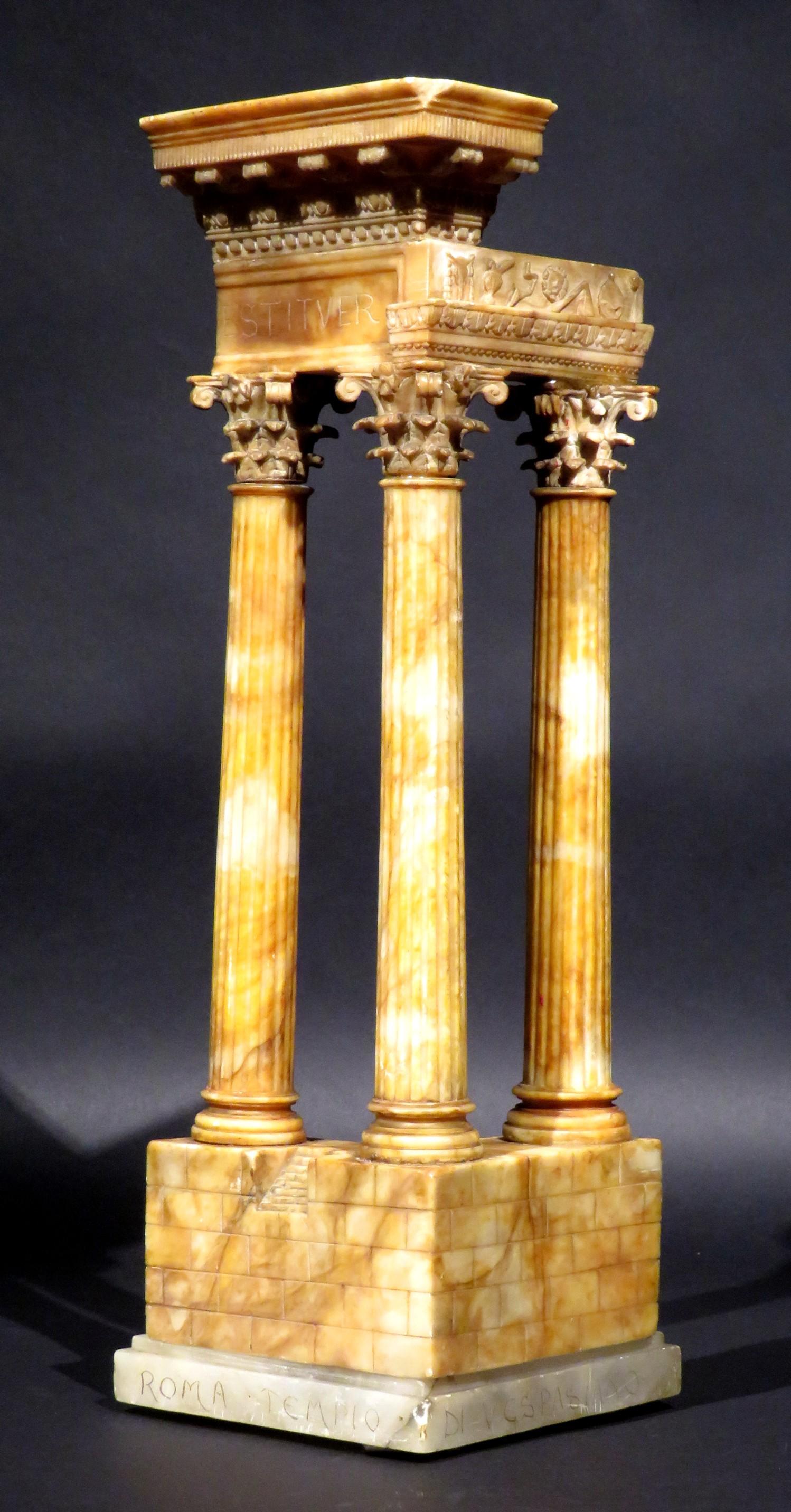 Die große und fein gemeißelte Alabasterkonstruktion zeigt ein Trio kannelierter Säulen, die in fein geschnitzten korinthischen Kapitellen enden und ein Gebälk mit einem geschnitzten Fries tragen, das Symbole der priesterlichen Collegia von Rom