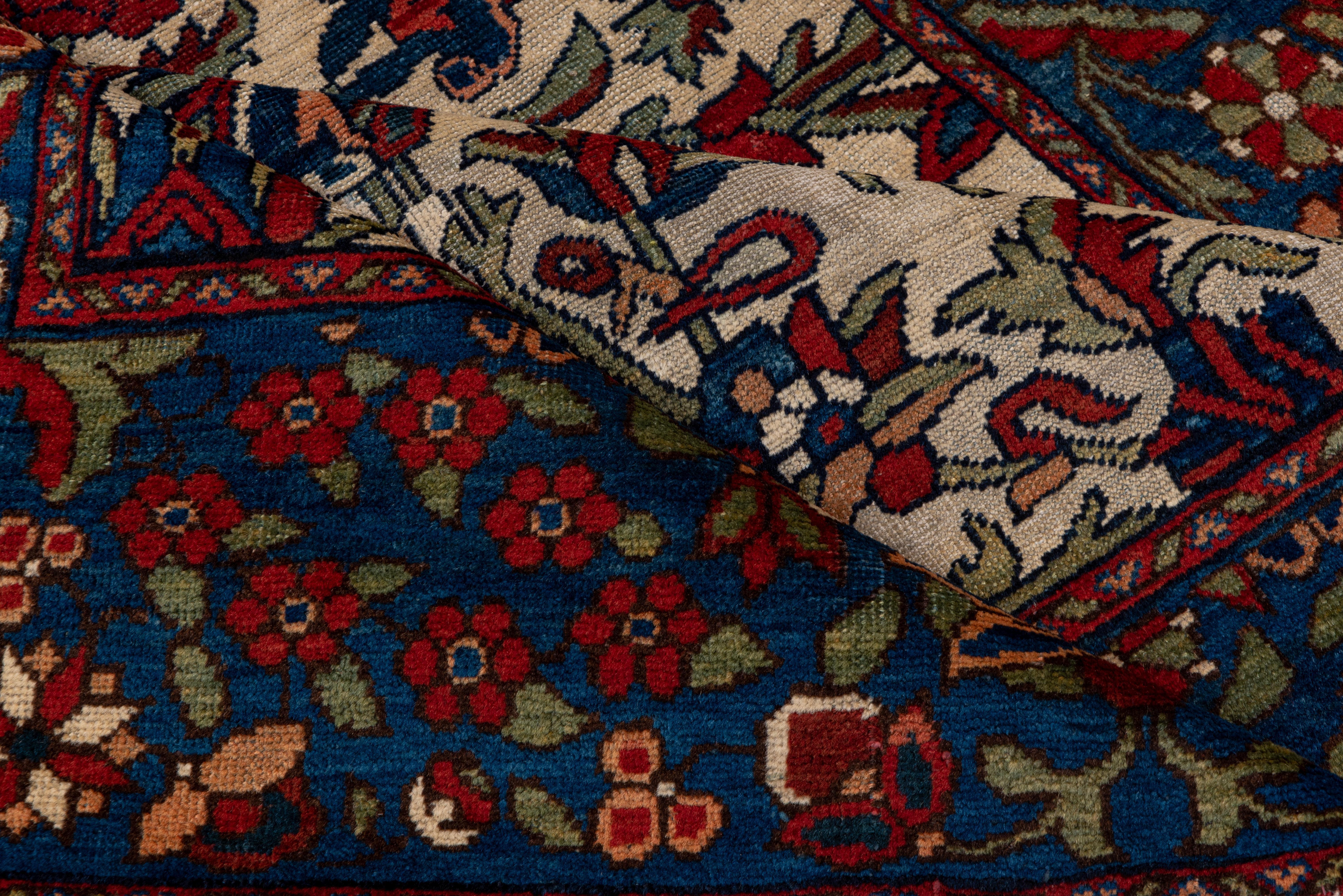 This striking West Persian rustic scatter shows a sand field with a barbed and serrated, bitonal sickle leaf and palmette pattern, with vigourous connecting vinery. Broad cerulean blue border with layered rosettes and petal palmettes Good madder red