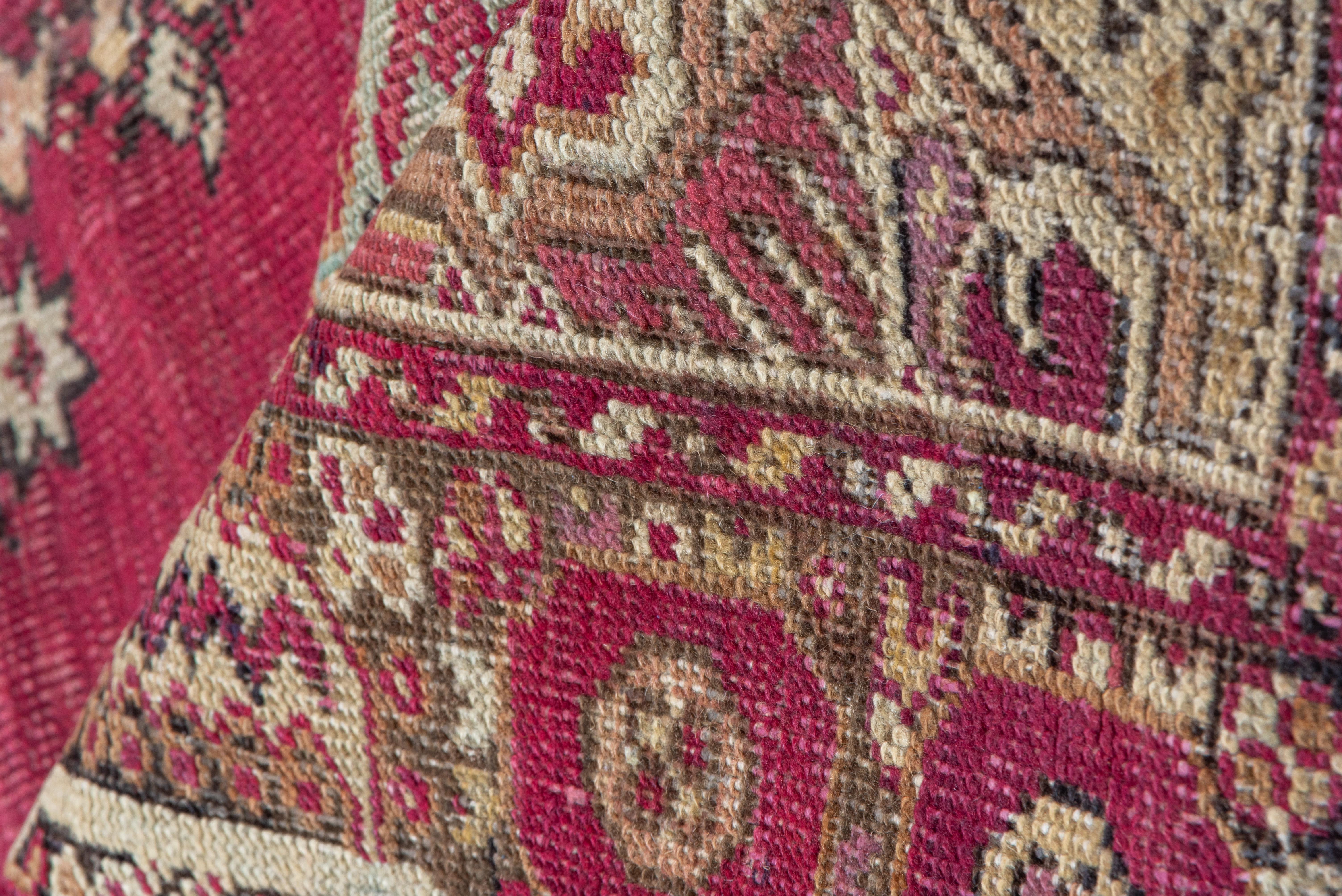 From the legendary West Anatolian town of Ghiordes, the abrashed magenta field is centered by a rosette and carnation lozenge medallion, within deep straw-sand fricomb-leafand small stepped gul all-over pattern. Cloud band extra panels at field