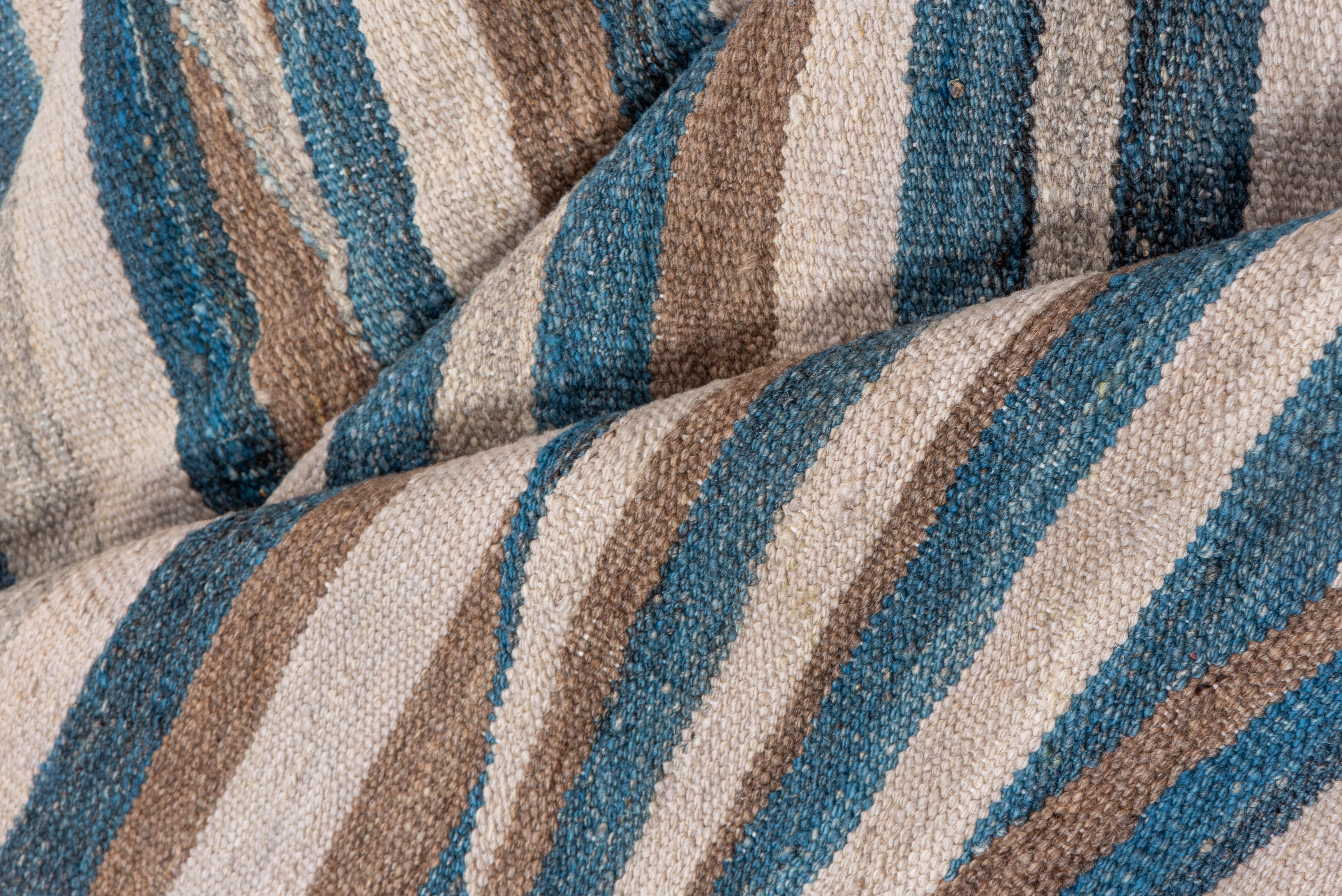 A beautiful wave-like pattern is woven on this flatweave rug from Afghanistan. Tones include browns, taupes and blues with striations. A beautiful modern piece!