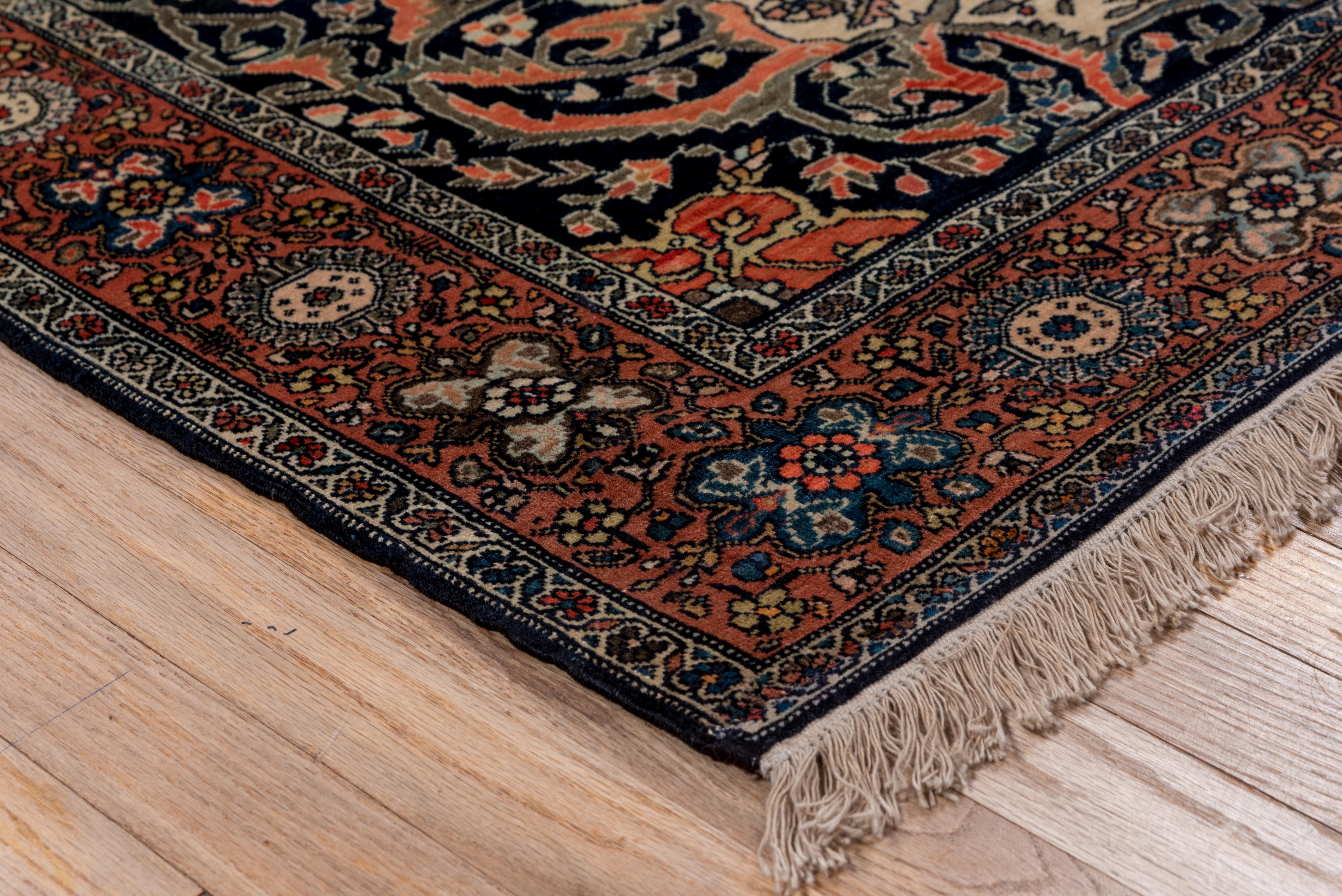 This well woven, leathery textured village scatter displays a buff cartouche medallion, with a four direction near black and dark blue sub-medallion, on a cream ground decorated with flowering broken tendrils, set with near black corners featuring