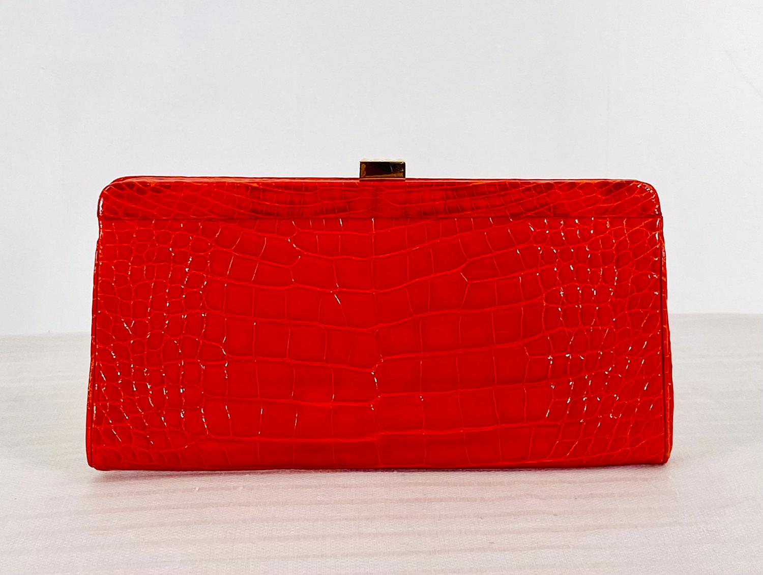 Finesse La Model glazed orange alligator clutch handbag. Great bag for afternoon or evening in a beautiful shade of orange. Frame bag with a gold clasp closure, the interior is orange suede with a single zipper compartment inside. In very good