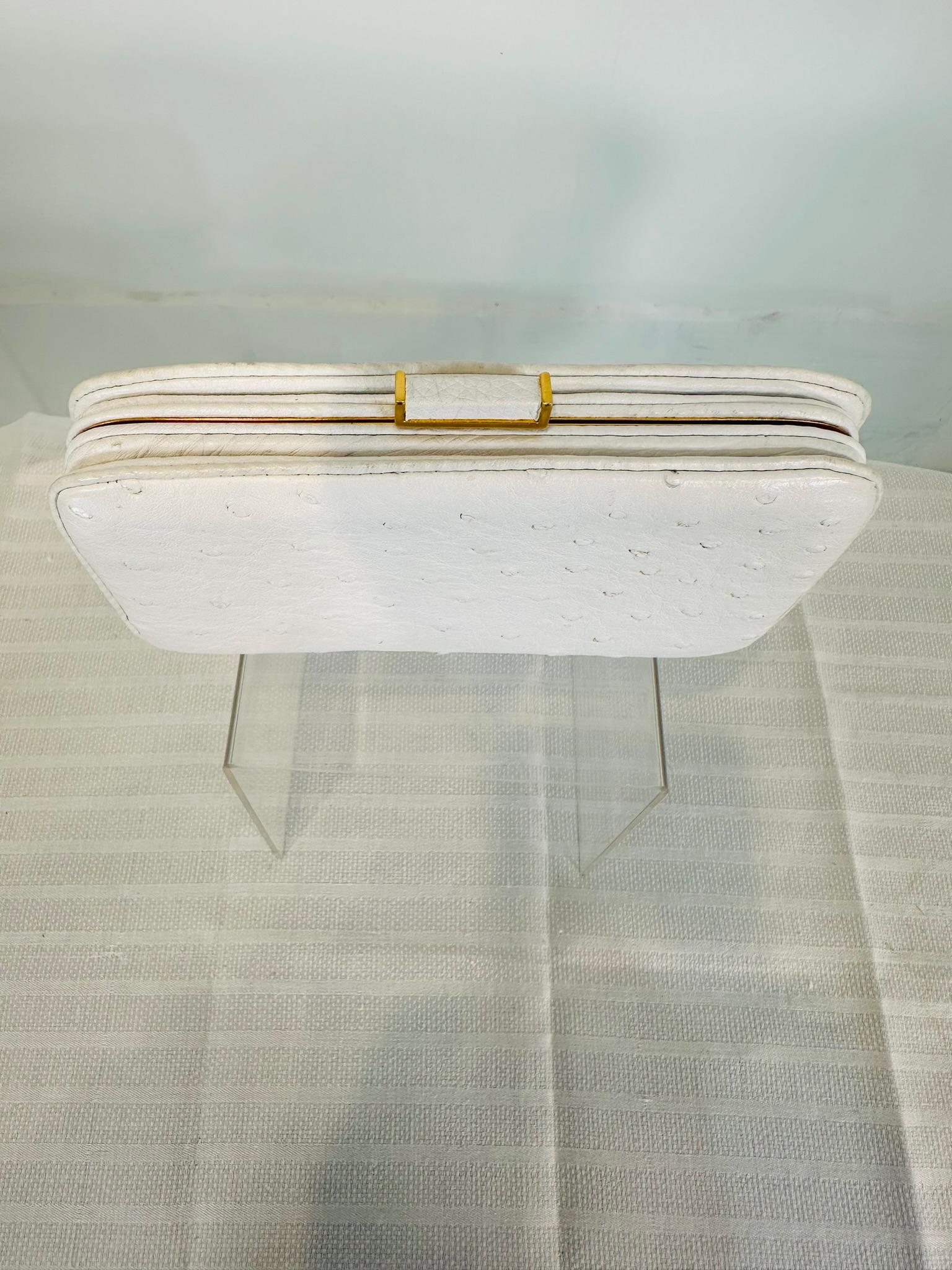 Finesse La Model white ostrich clutch bag with gold hardware. From the 1990s, this is a beautiful little bag made in white ostrich leather with matte gold frame. The bag closes with a rectangle clasp of white ostrich framed in matte gold. The bag is
