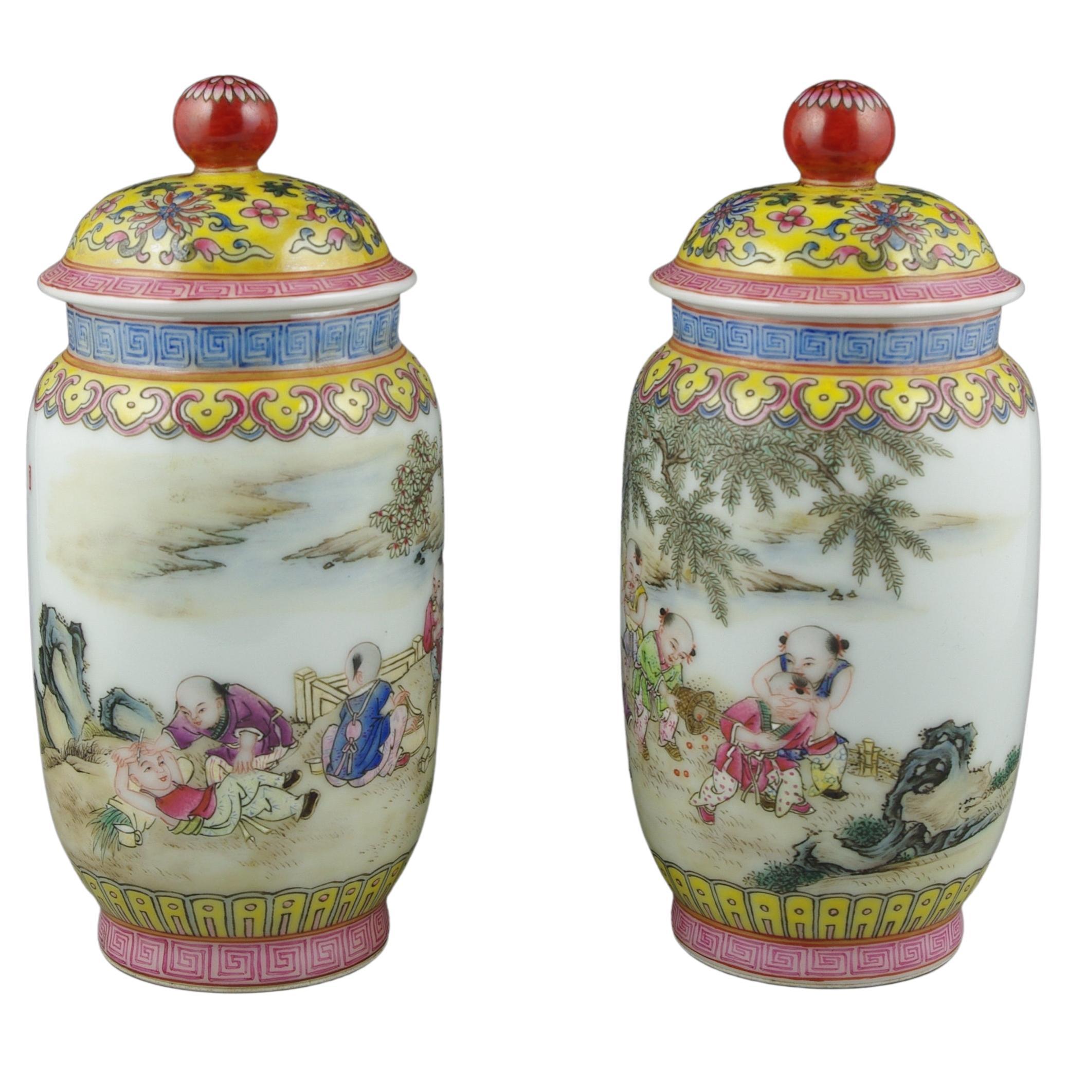 Une exquise paire de jarres couvertes chinoises, splendide représentation de la riche tapisserie de l'art chinois et de l'artisanat le plus raffiné. Chaque pot est une toile vibrante qui raconte une délicieuse histoire d'enfance, dépeinte à travers