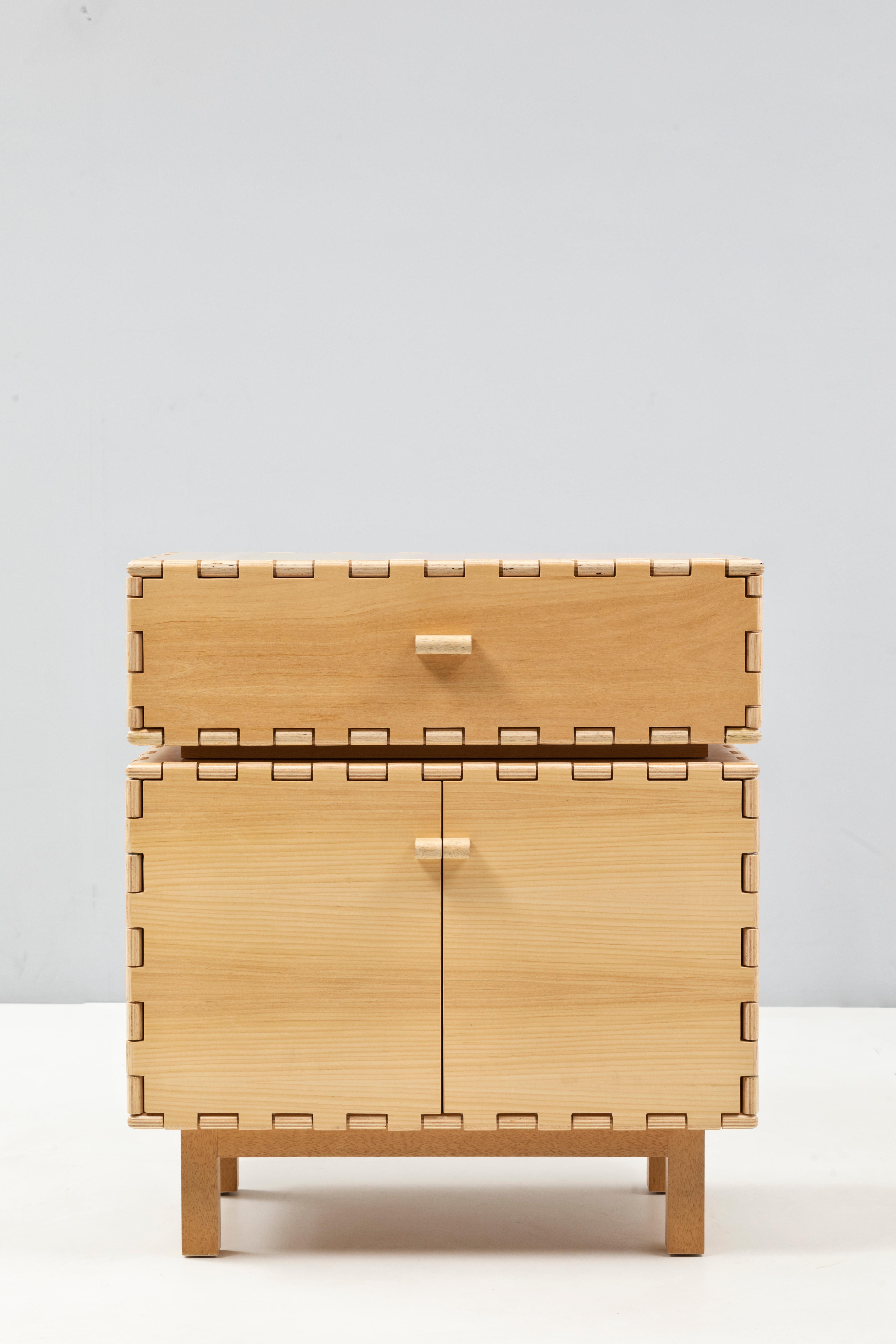 Handcrafted cabinet in natural wood. The lacquer color highlights the simplicity of the interlocking panels design. The modular quality of the collection allow each cabinet to be combine with other pieces within the collection to create different