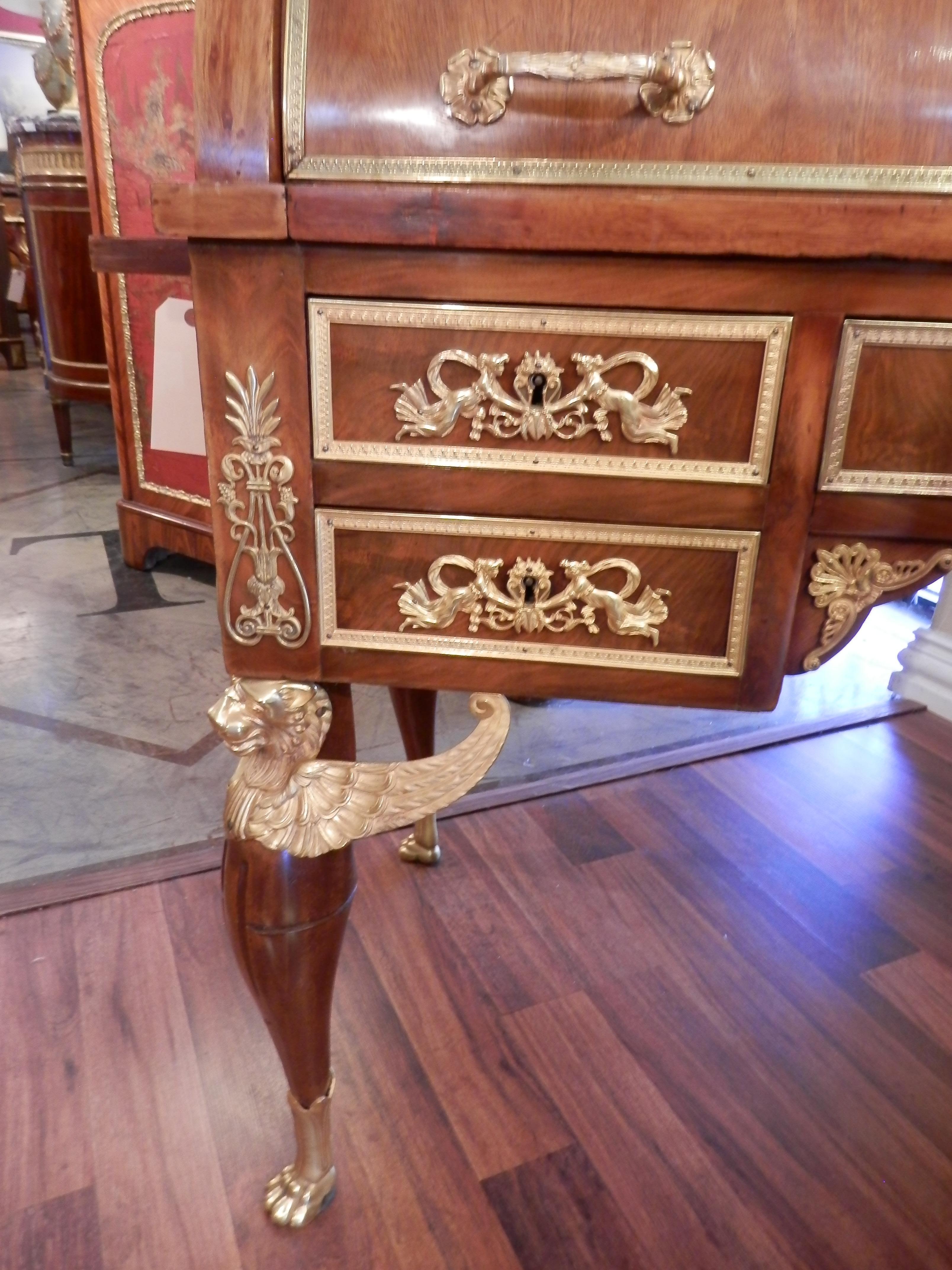 Finest quality 19th century Empire mahogany and gilt bronze roll top desk. The drawers lined with a green silk. The writing surface is a red leather . The gilt bronze Empire details are very finely detailed with the original gilt bronze . The desk