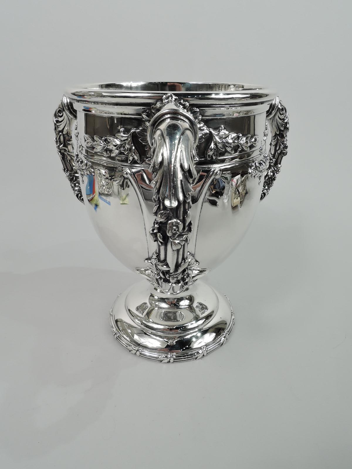 Turn-of-the-century Gilded Age sterling silver loving cup. Made by Theodore B. Starr in New York. Curved and tapering bowl on double-domed foot. Three leaf-mounted and -capped garland-entwined handles. Chased leaves. Reeding. Curvilinear strapwork