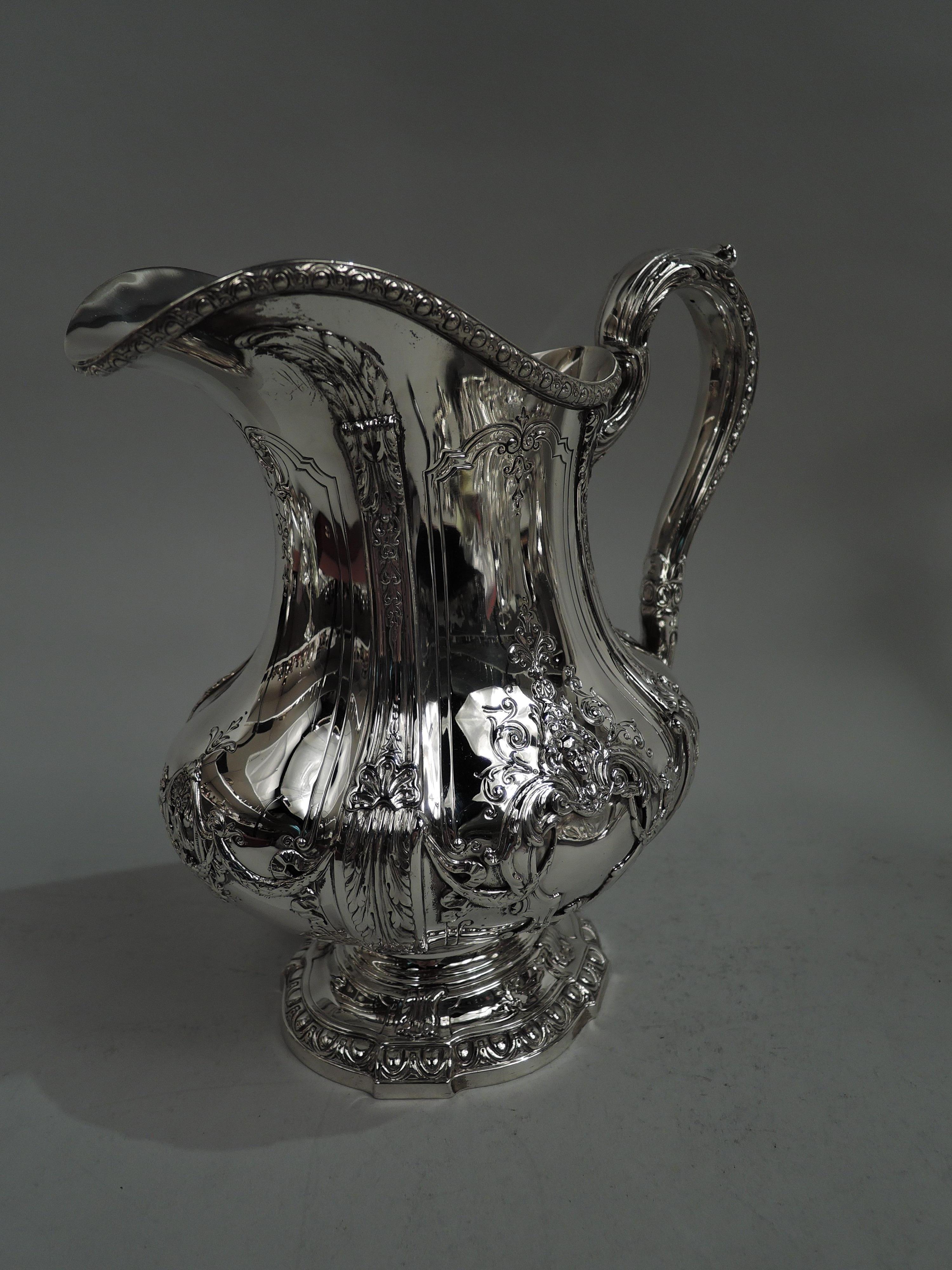 Finest quality sterling silver water pitcher in Louis XV pattern. Made by Reed & Barton in Taunton, Mass., ca 1920. Ovoid baluster with leaf and shell pilasters. Helmet mouth and beaded leaf-capped and -mounted high-looping scroll handle; foot