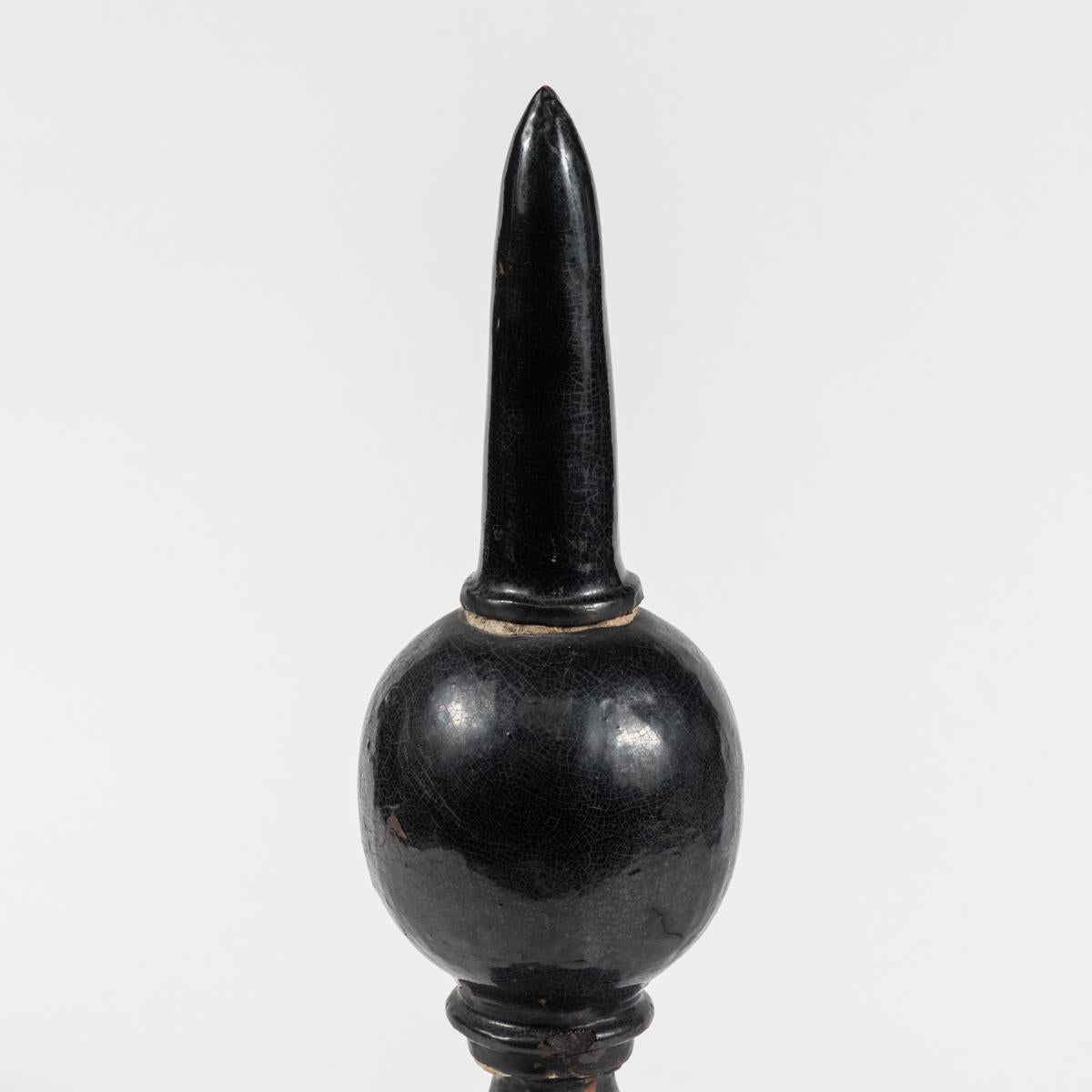 This is a 19th century terracotta finial from England. There is a black glaze applied over the surface of the object, giving it a uniquely aged appearance. 