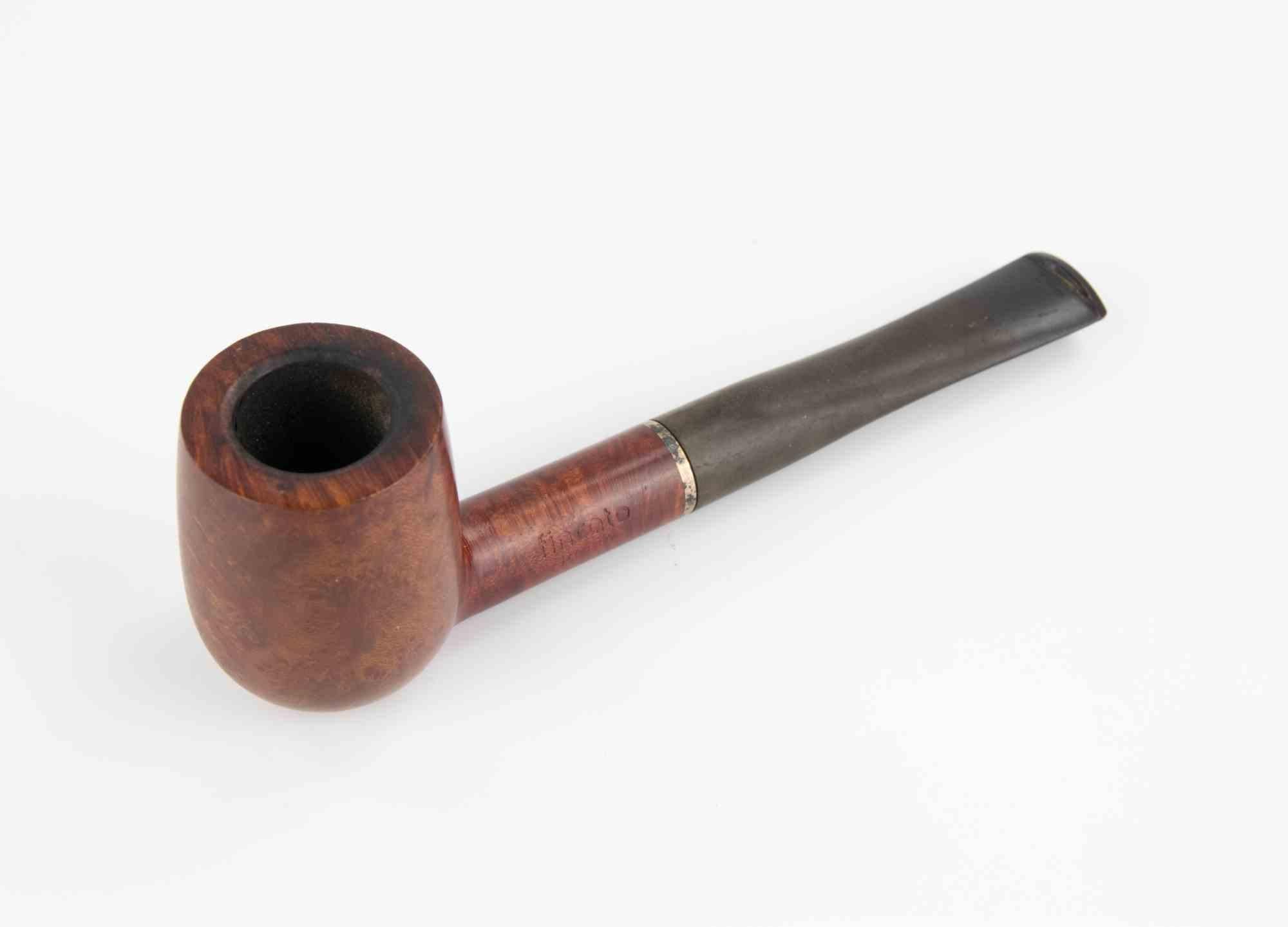 Pipa vintage di Finicarto Roma.

La ciotola è realizzata in radica liscia con una tinta marrone rossastra che esalta le venature naturali del legno. La sua forma è classica e sobria, caratterizzata da linee dritte e pulite che sottolineano