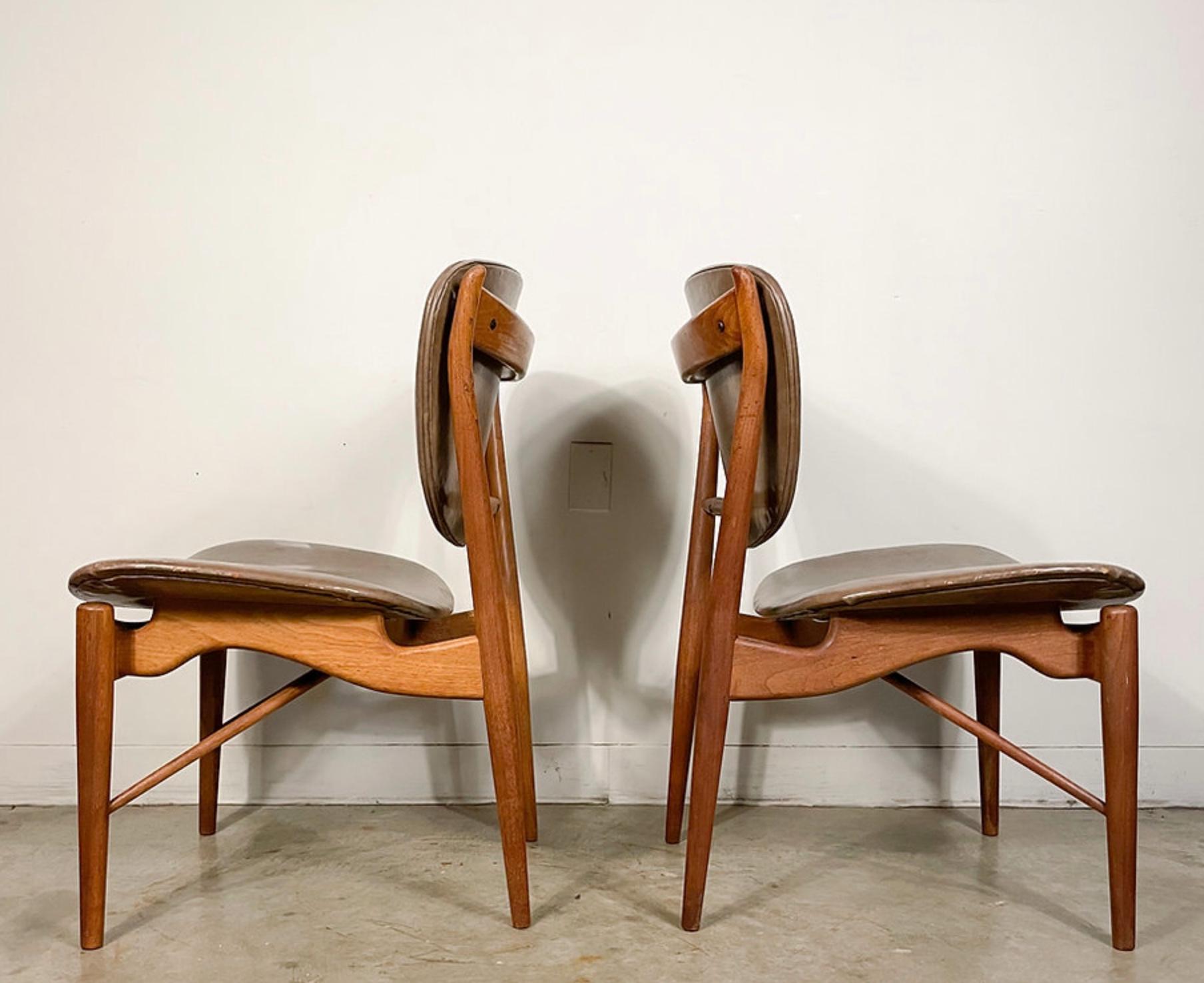 This pair of beautiful Finn Juhl Model 51 Chairs were made by Baker Furniture circa 1952 for the Baker Modern line. They offer solid walnut frames with distinctive 'horns', undulating curves, and dynamic angled stretchers. Both chairs feature