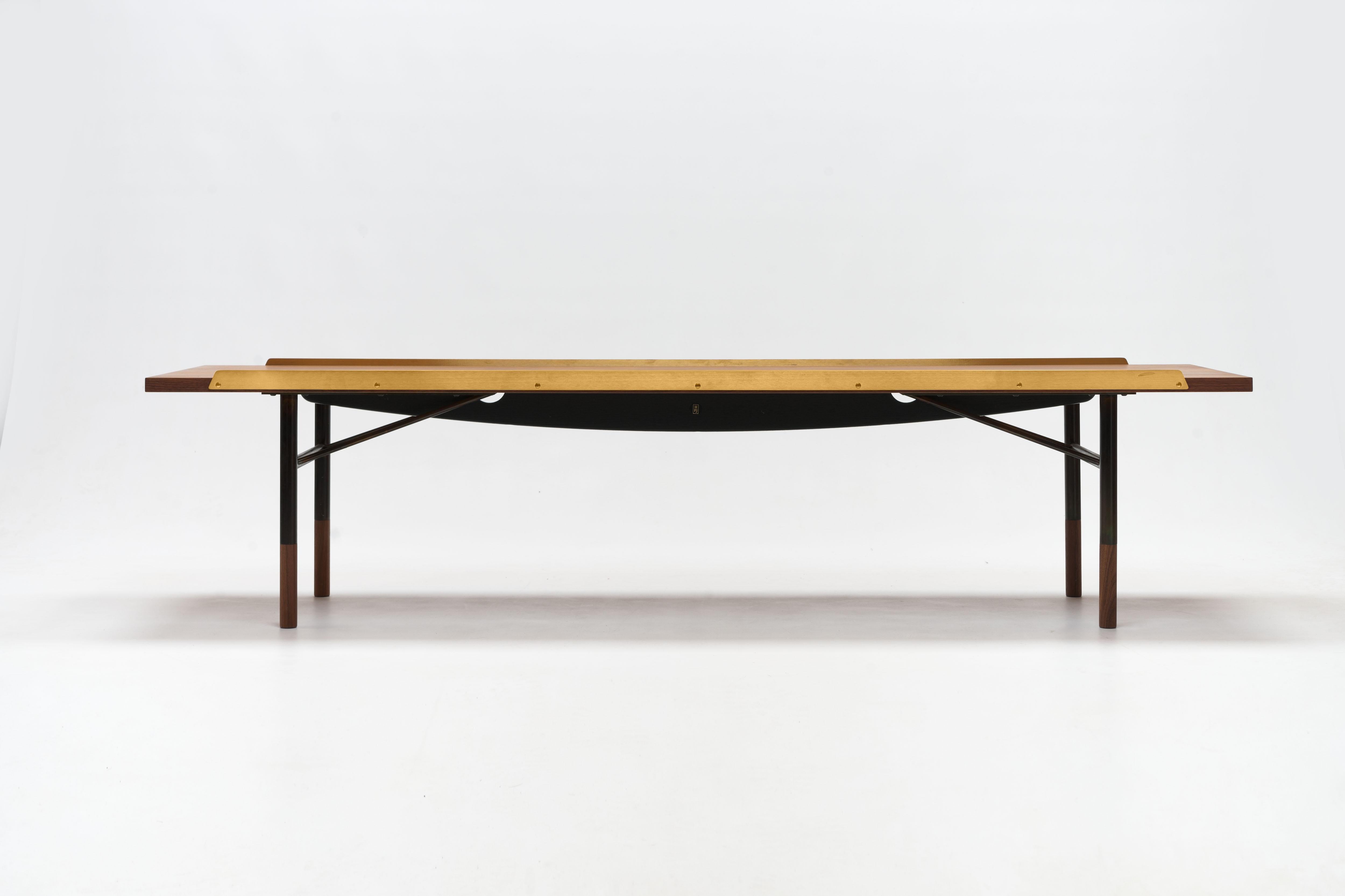 Low bench table by Finn Juhl in walnut with brass edges by One Collection / House of Finn Juhl with loose cushion in SONAR #734 fabric by Raf Simons for Kvadrat. 

This versatile piece can be used free standing as a bench or coffee table or as a