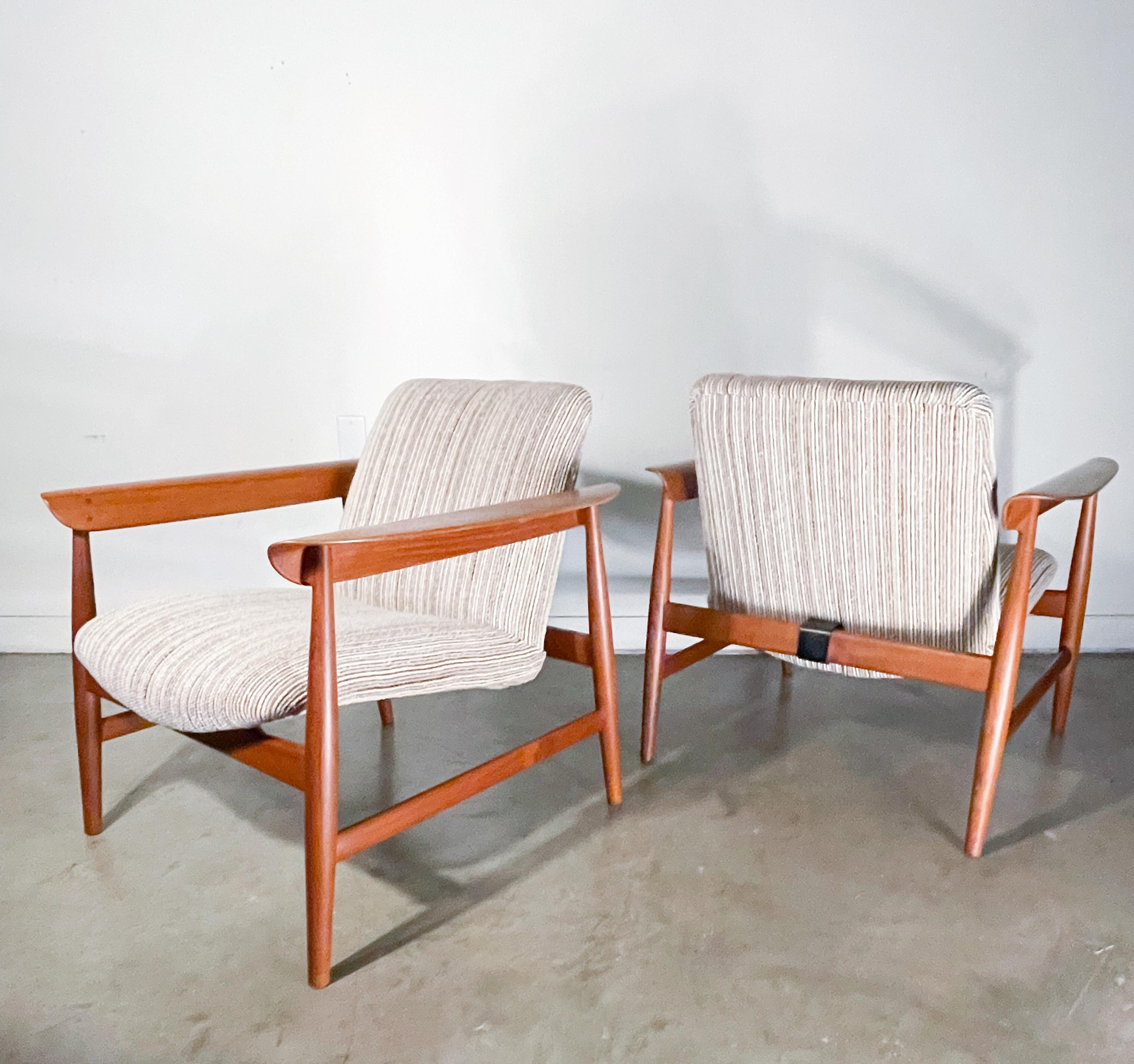 Rare and collectible lounge chairs designed by the masterful Finn Juhl for Bovirke of Denmark. Solid teak frames with bent teak plywood arms cradle an upholstered steel tube seat frame. Distinctive armrests with subtle dowel head details, sculpted