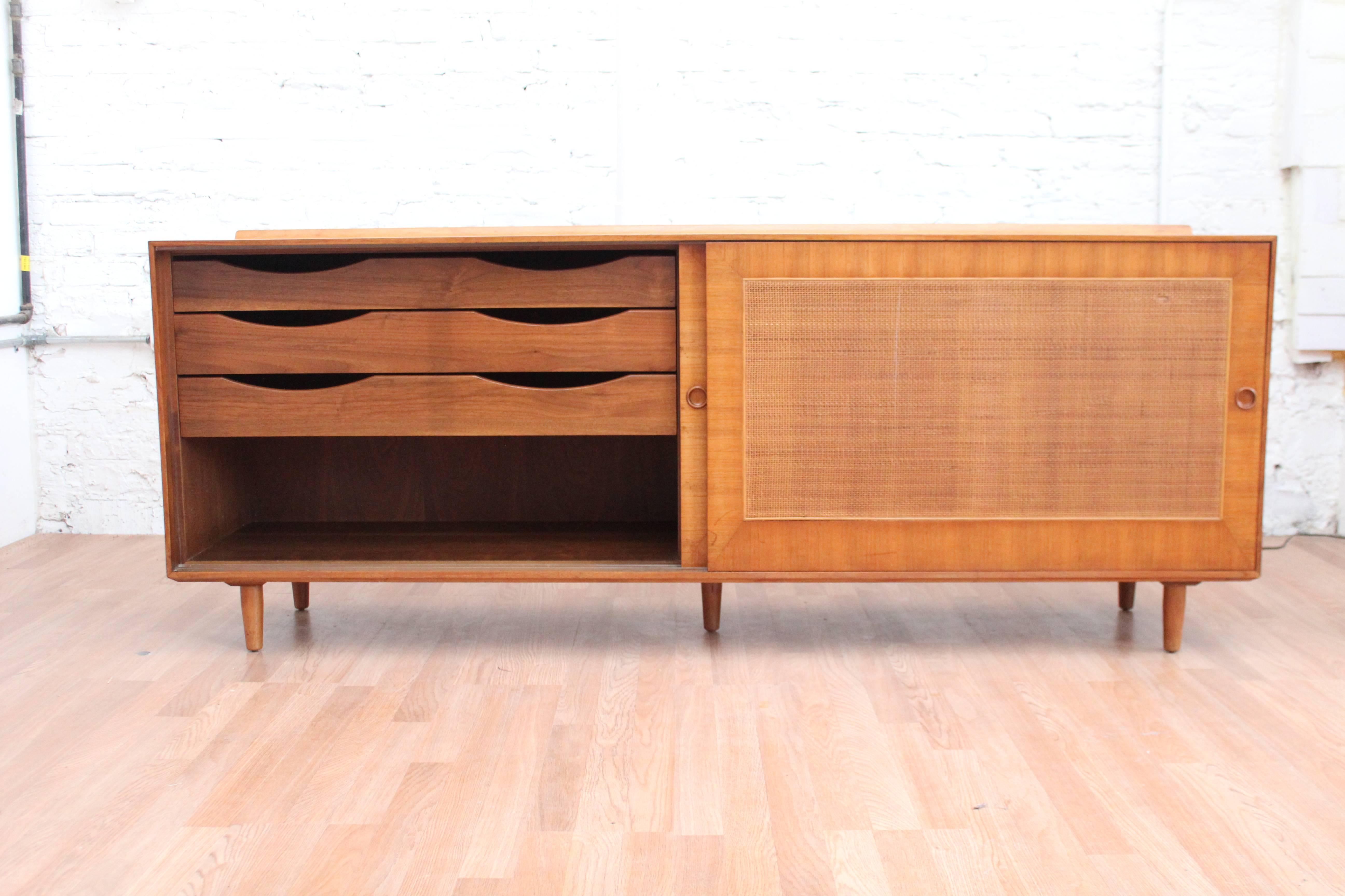 Attention all Purist! Imagine adding this original finish, Finn Juhl for Baker, period credenza to your collection! This magnificence features two sliding doors that conceal an adjustable shelf and three pull-out drawers. The case sits on five