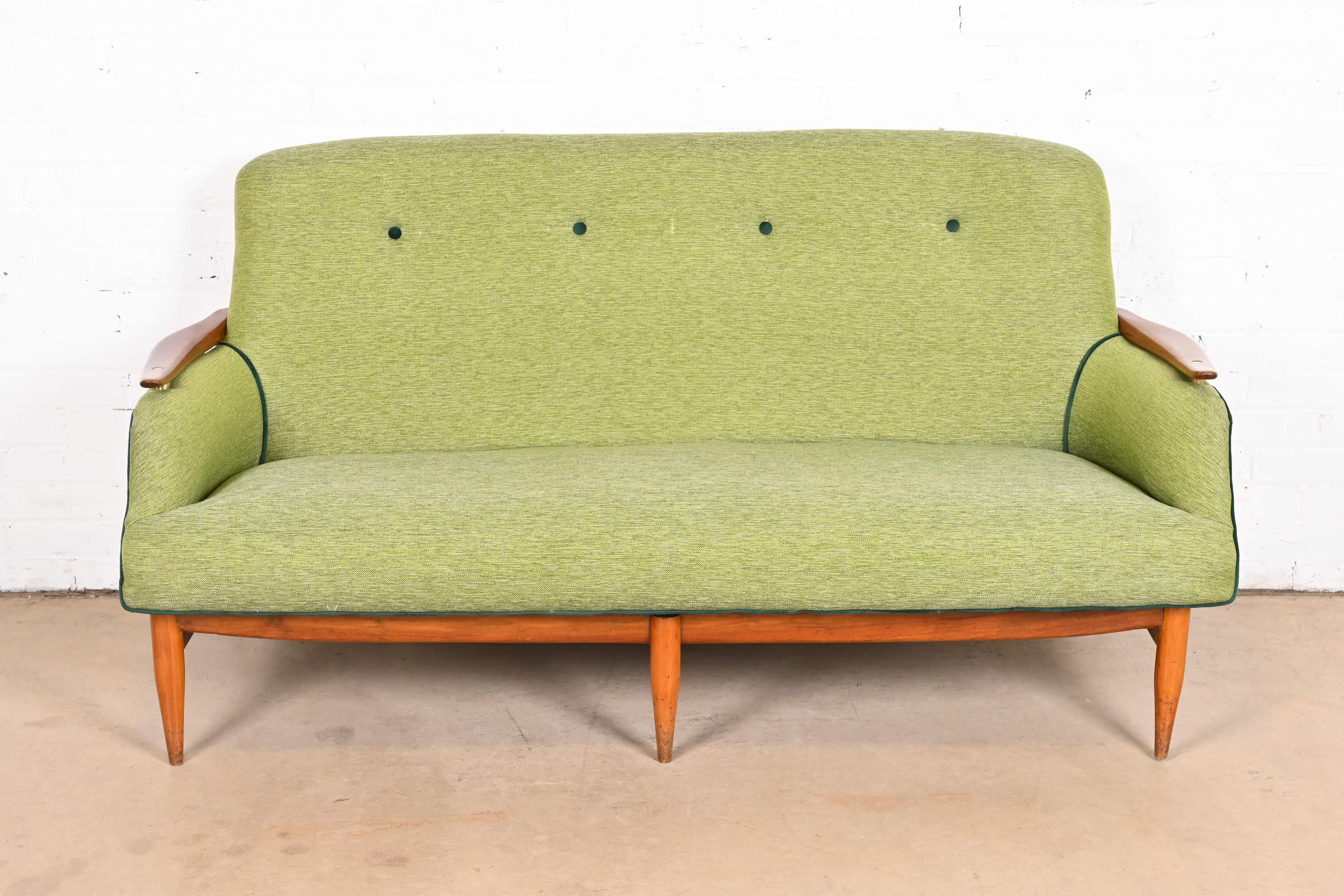 Ein wunderschönes dänisches modernes Sofa aus der Mitte des Jahrhunderts

Zuschreibung an Finn Juhls

Dänemark, 1950er Jahre

Rahmen aus geschnitztem Teakholz mit Messingakzenten, grün gepolstertem Sitz und getufteter Rückenlehne.

Maße: 64 