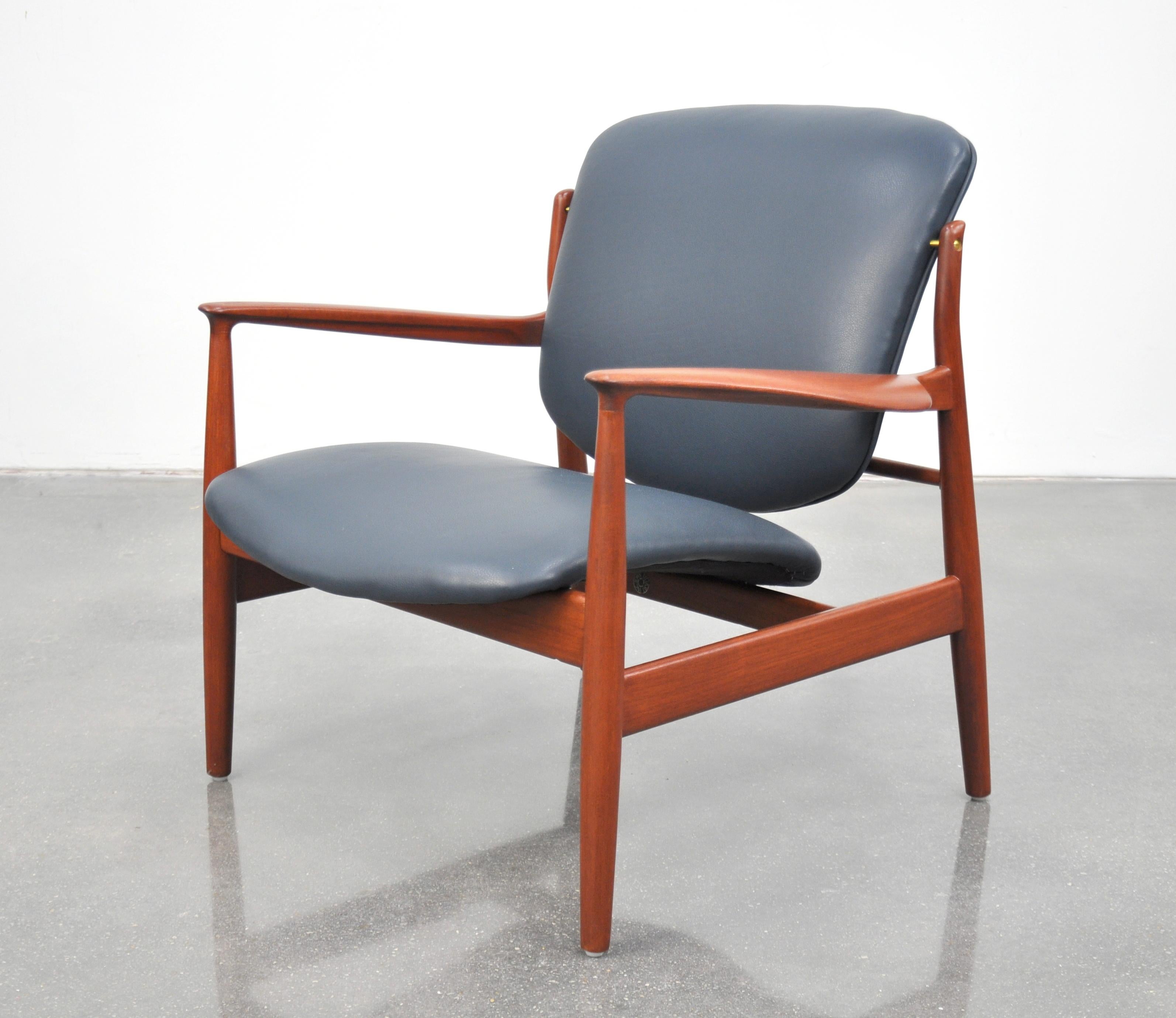 An iconic Mid-Century Danish Modern FD136 easy chair designed by Finn Juhl for France and Daverkosen (later named France and Son) in the 1950s. The seat and backrest have been reupholstered in a gorgeous dark blue pebbled leather. The splendidly