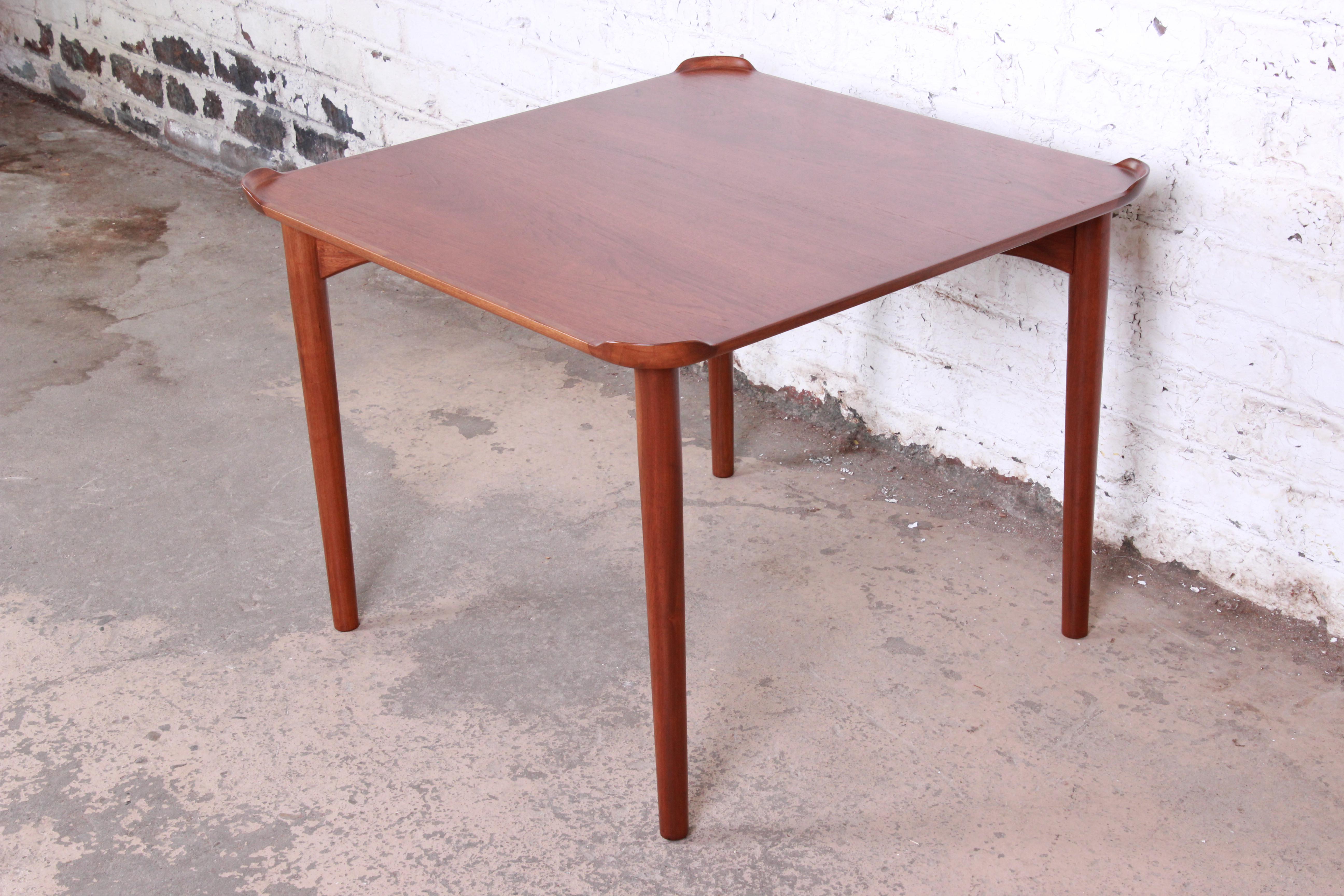 A handsome teak game table designed by Danish architect Finn Juhl for Baker Furniture. The table features stunning teak wood grain and unique carved corner drink backsplashes. Minimalist mid-century Danish Modern design at its finest. The table has