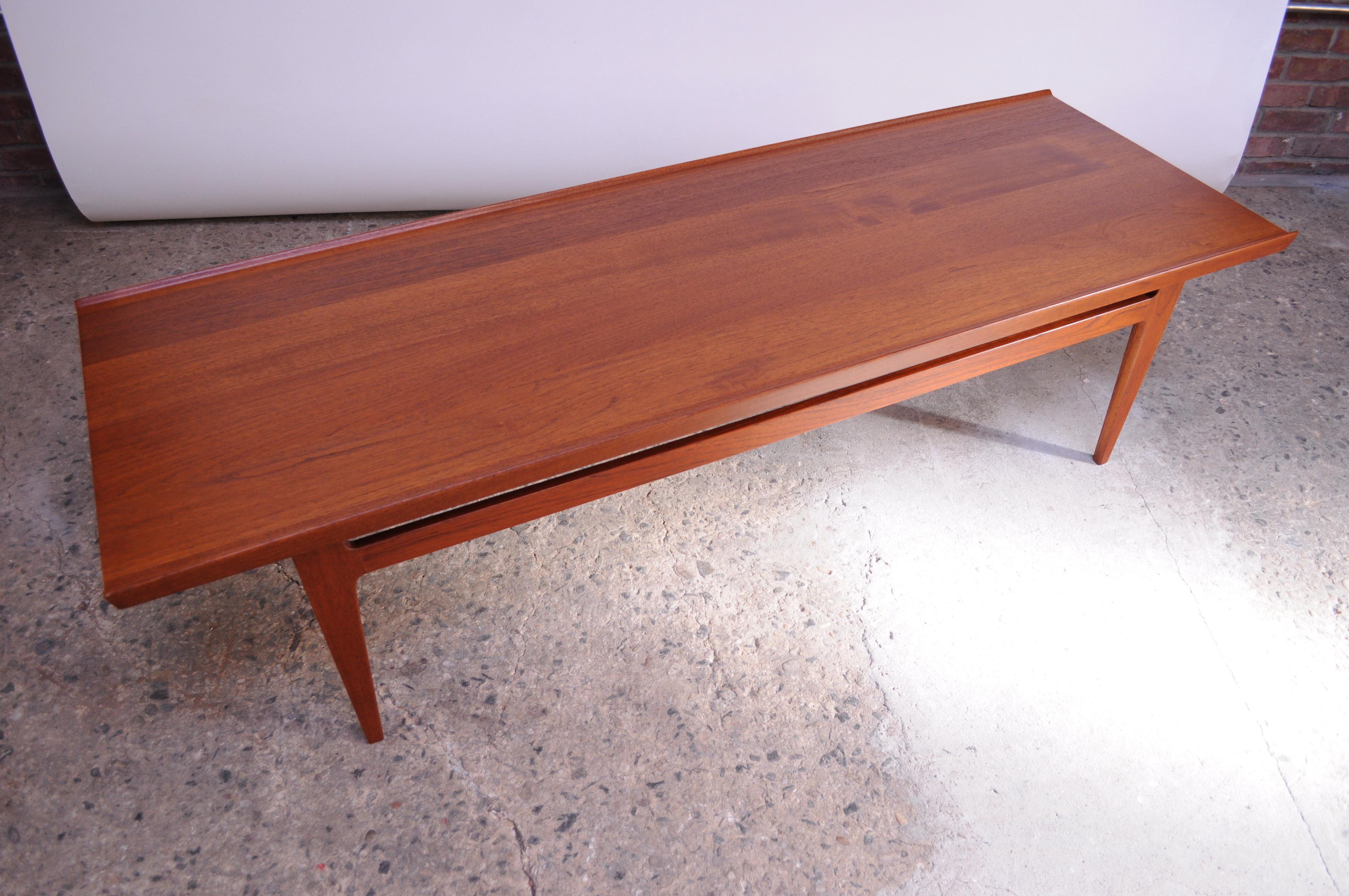 Model # 532 rectangular coffee table designed by Finn Juhl and produced by France & Son (circa 1959). Sculpted from solid teak featuring lipped edges and unique, tapered legs. Conservatively refinished and in excellent, vintage condition. 
Retains