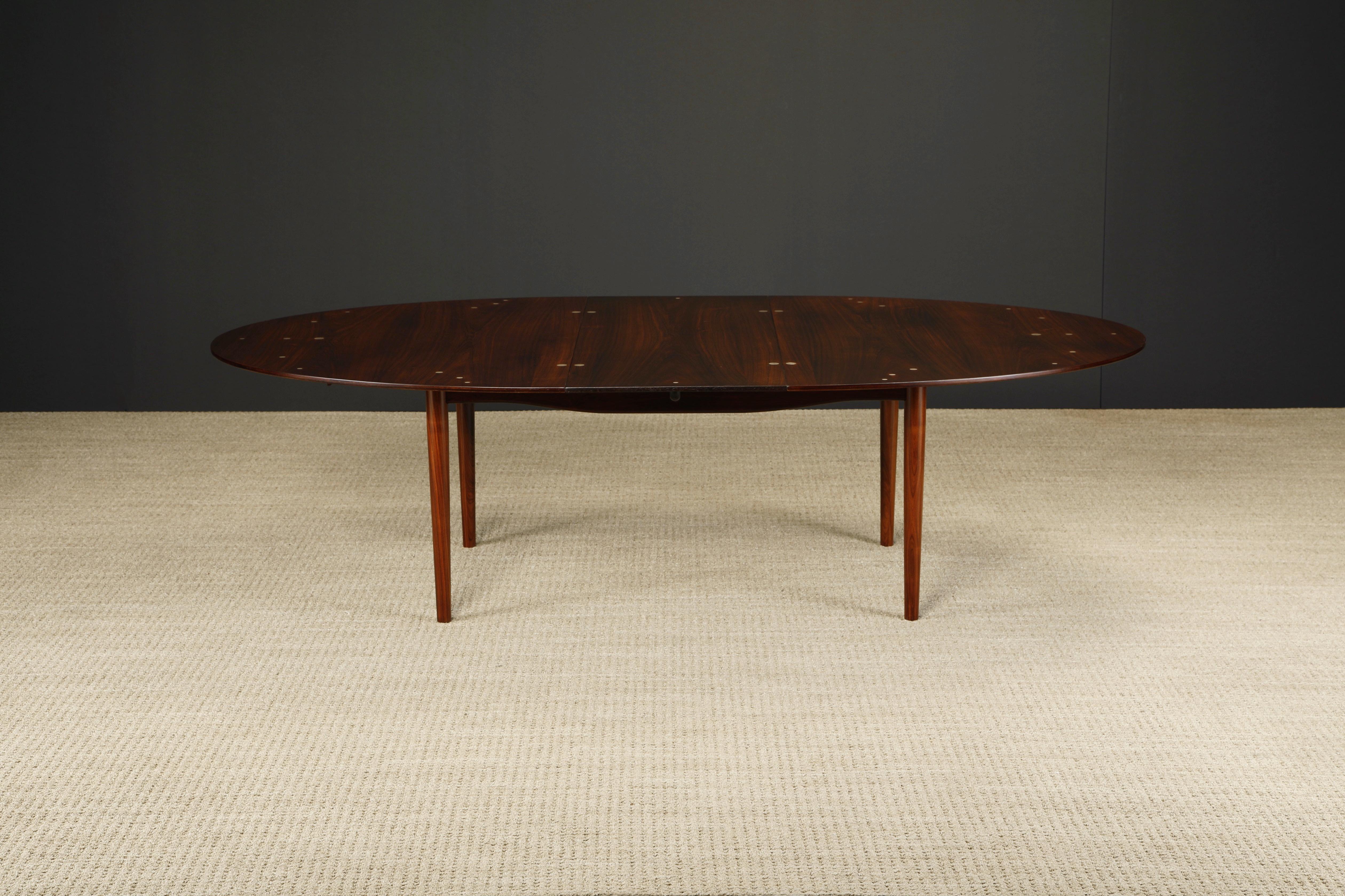 Exceptionally rare and sought after, this Finn Juhl for Niels Vodder 'Judas' dining table, 1950s Denmark, was professionally restored and features gorgeous Brazilian Rosewood with sterling silver inlaid medallions which assist in tableware placement