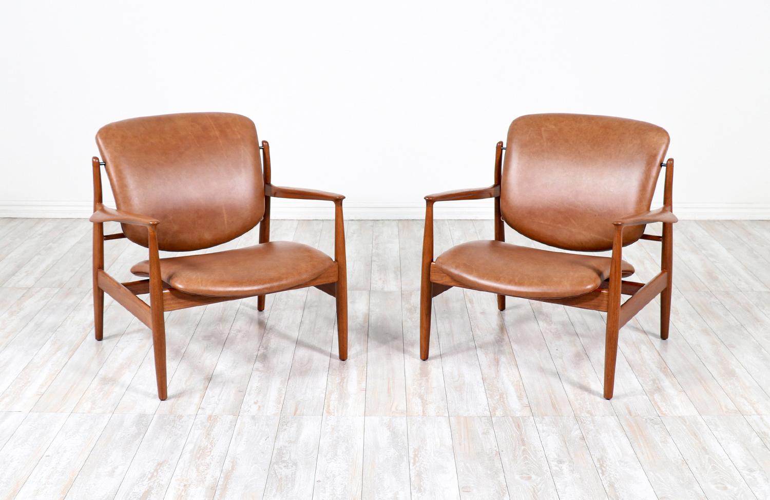 Model FD-136 chairs designed by Finn Juhl for France & Daverkosen in Denmark circa 1950’s. This pair of open wood frame lounge chairs feature a teak structure with sculpted armrests and have been reupholstered with the highest quality full-grain