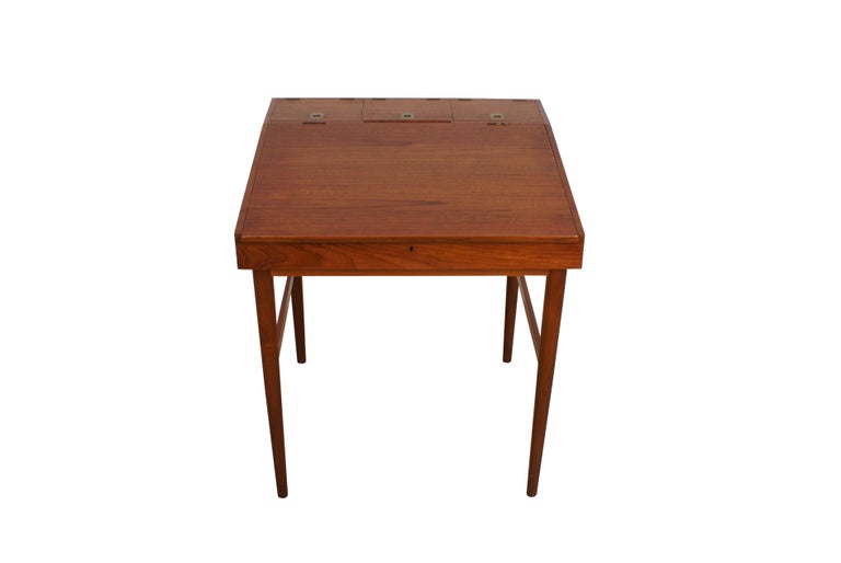 Finn Juhl writing desk in teak for cabinetmaker Niels Vodder. Tapering legs. Writing top with storage space, three small compartments with lids and brass handles.

Stamped from cabinetmaker Niels Vodder.