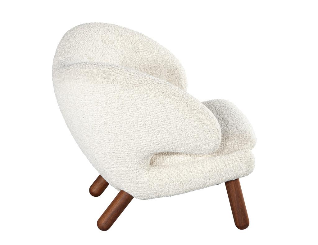The Finn Juhl Pelican Chair is a modern take on classic design. It is an iconic piece created by the famous Danish designer, Finn Juhl. This chair has sleek walnut legs and is upholstered in a textured boucle fabric for a luxurious feel. The model