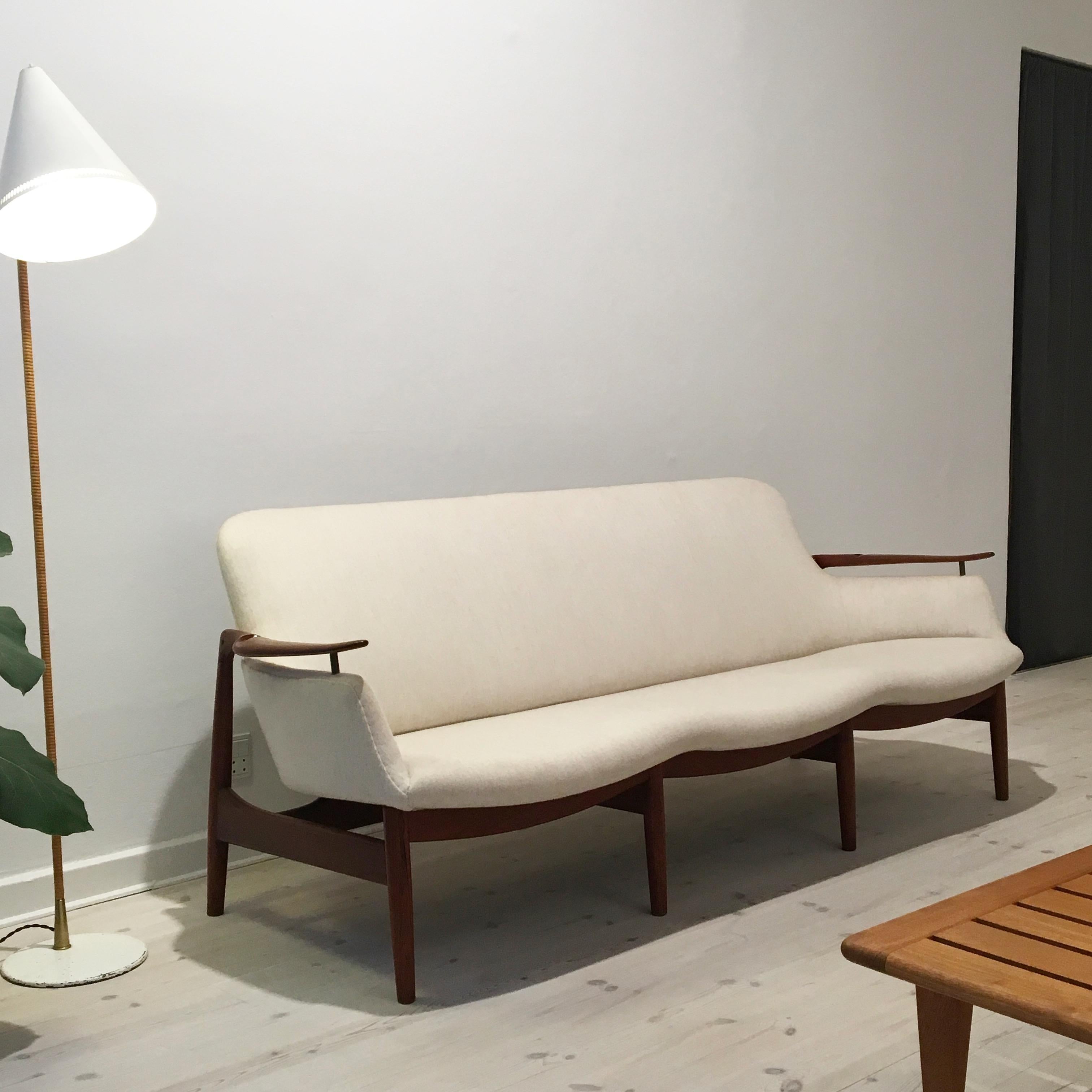 Finn Juhl NV53 three-seat sofa in teak and fabric for master cabinetmaker Niels Vodder. Sofa has been re-upholstered in Savak fabric (fabric designed by Tove Kindt-Larsen) and is finished with nails under the seat. It is very unusual to see this
