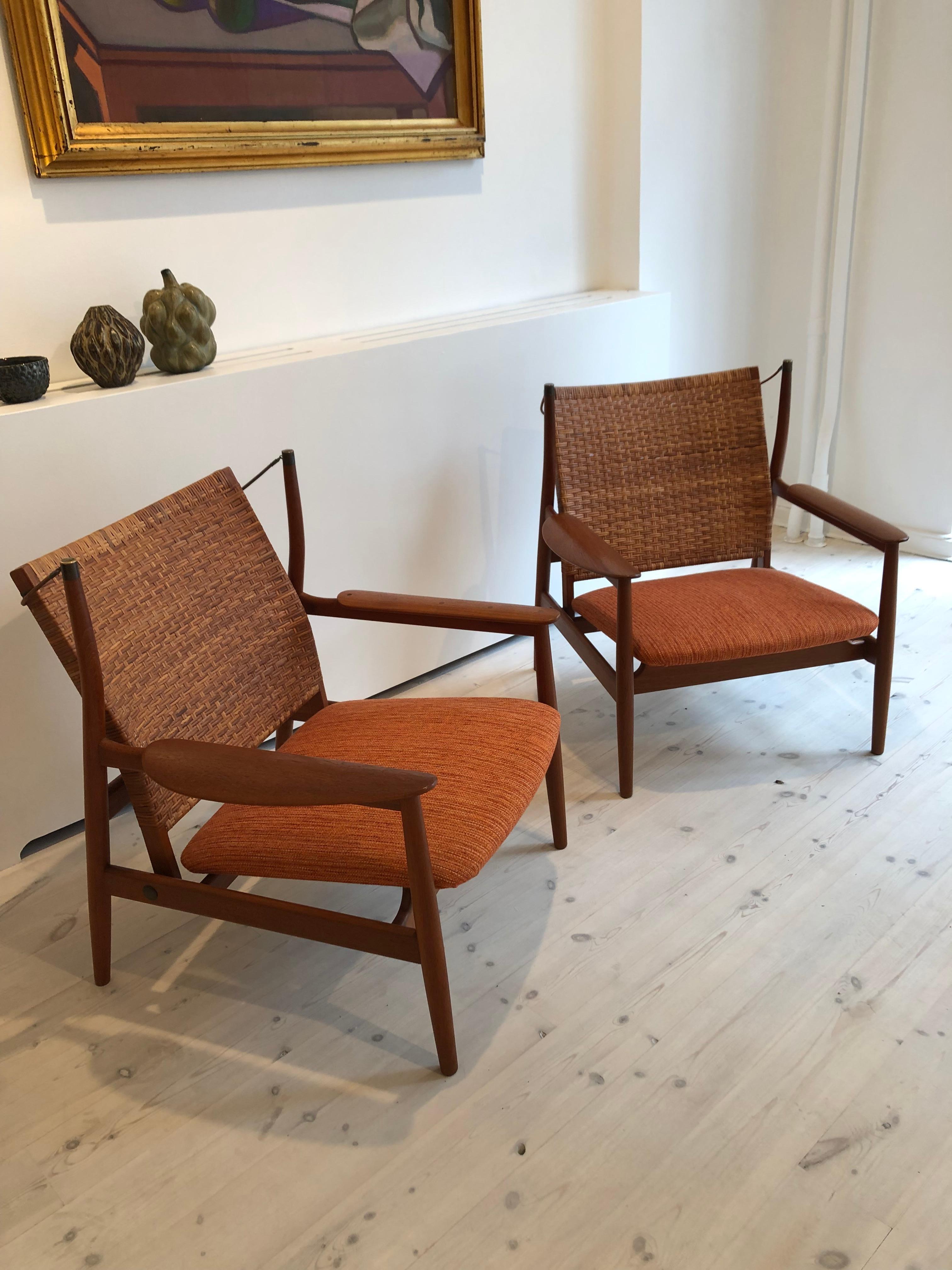 Finn Juhl, rare pair of teak NV55 armchairs for master cabinetmaker Niels Vodder with adjustable backs in cane. Seats in fabric. Each chair branded manufacturer’s mark to underside: 'Cabinetmaker Niels Vodder, Copenhagen Denmark, Design Finn Juhl'.