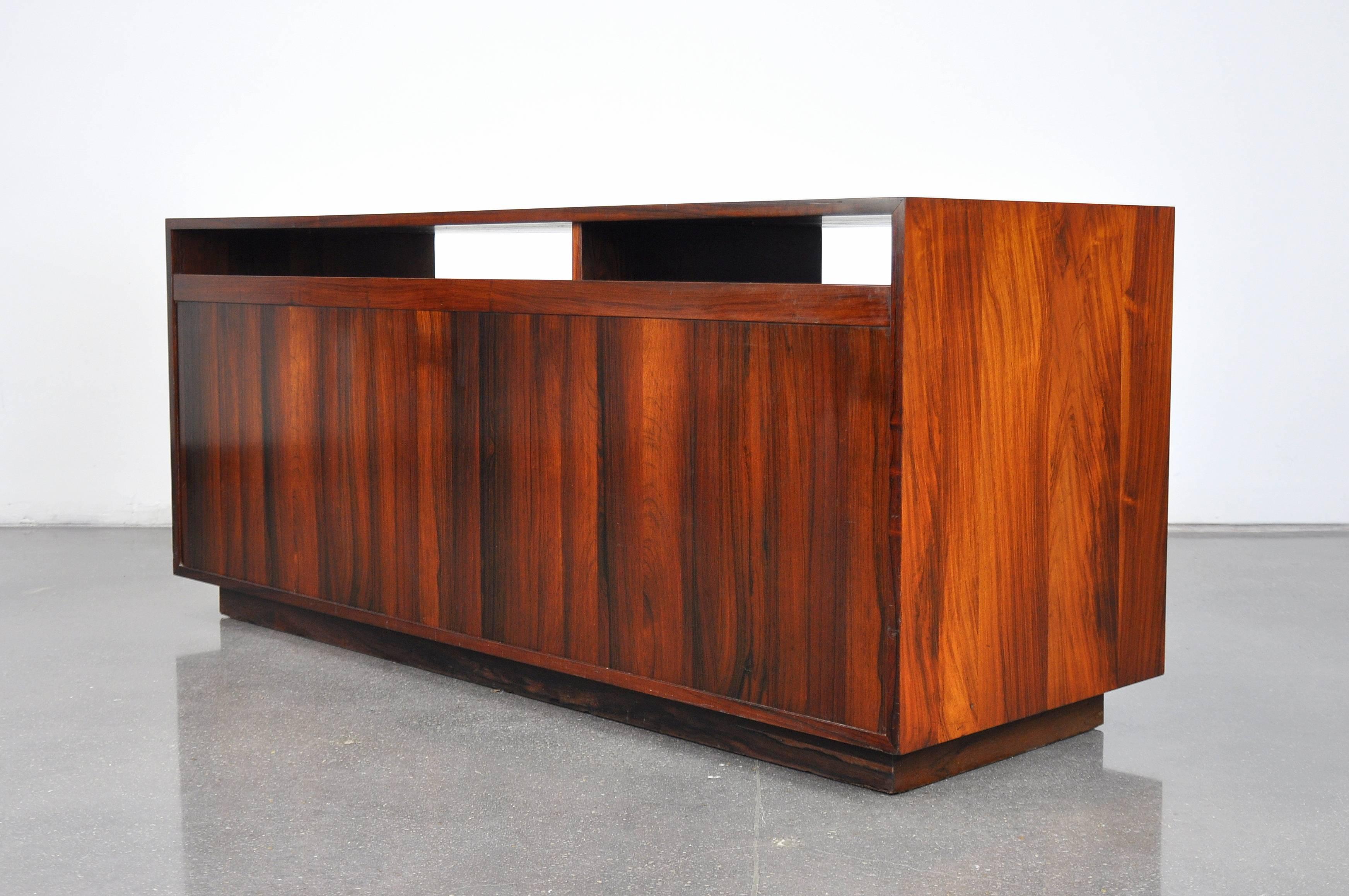 A superb Mid-Century Danish Modern cabinet designed by Finn Juhl for France and Son in 1959. The vintage sideboard, bar or buffet, with finished back features three sliding doors with signature aluminum pulls, opening to an interior with shelf,