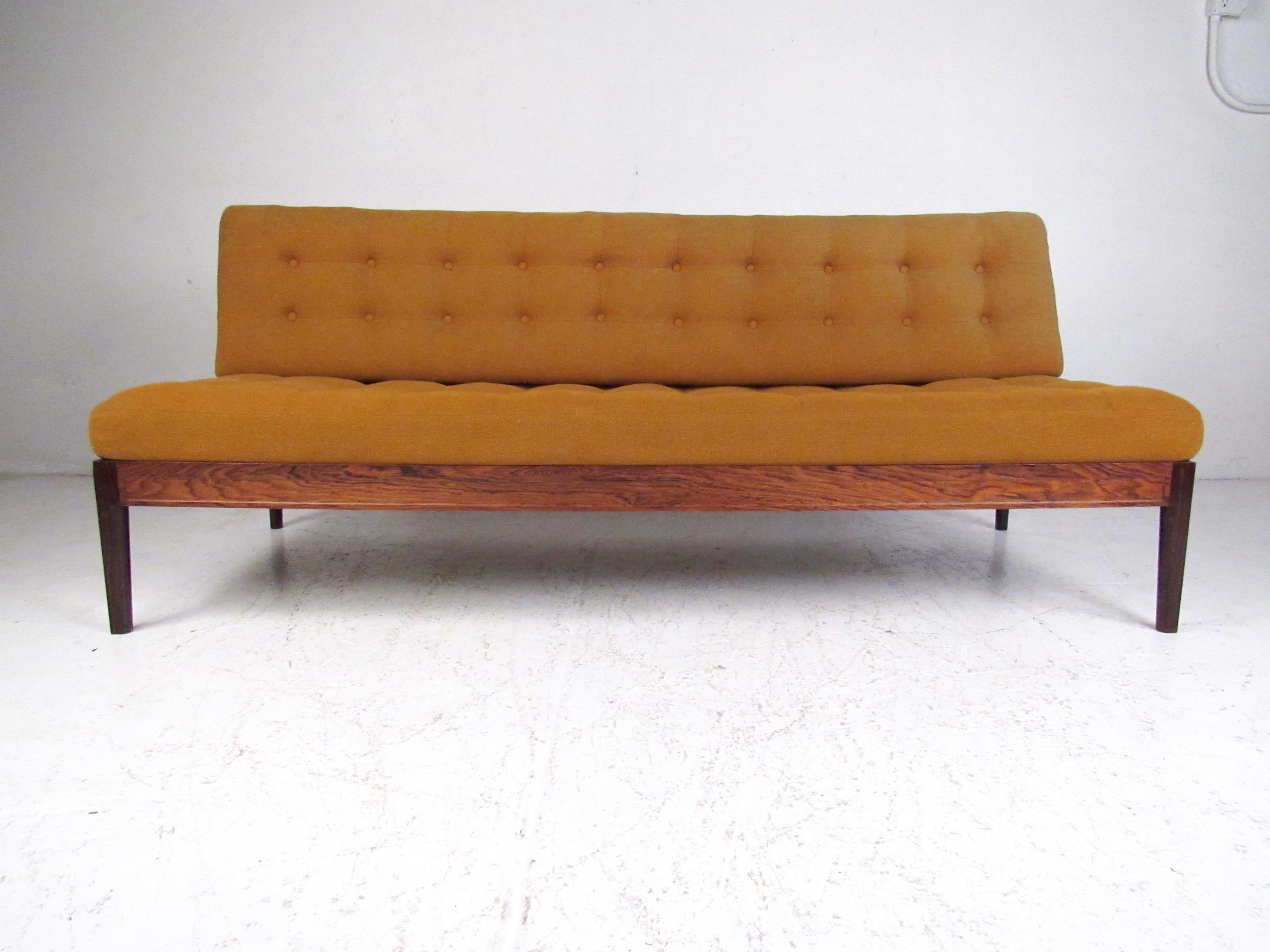 This stunning Mid-Century Modern sofa or daybed features rich rosewood finish, aluminum trim, vintage tufted upholstery, and impressive Scandinavian craftsmanship. With removable wedge seat back the sofa can be easily used as an office daybed for