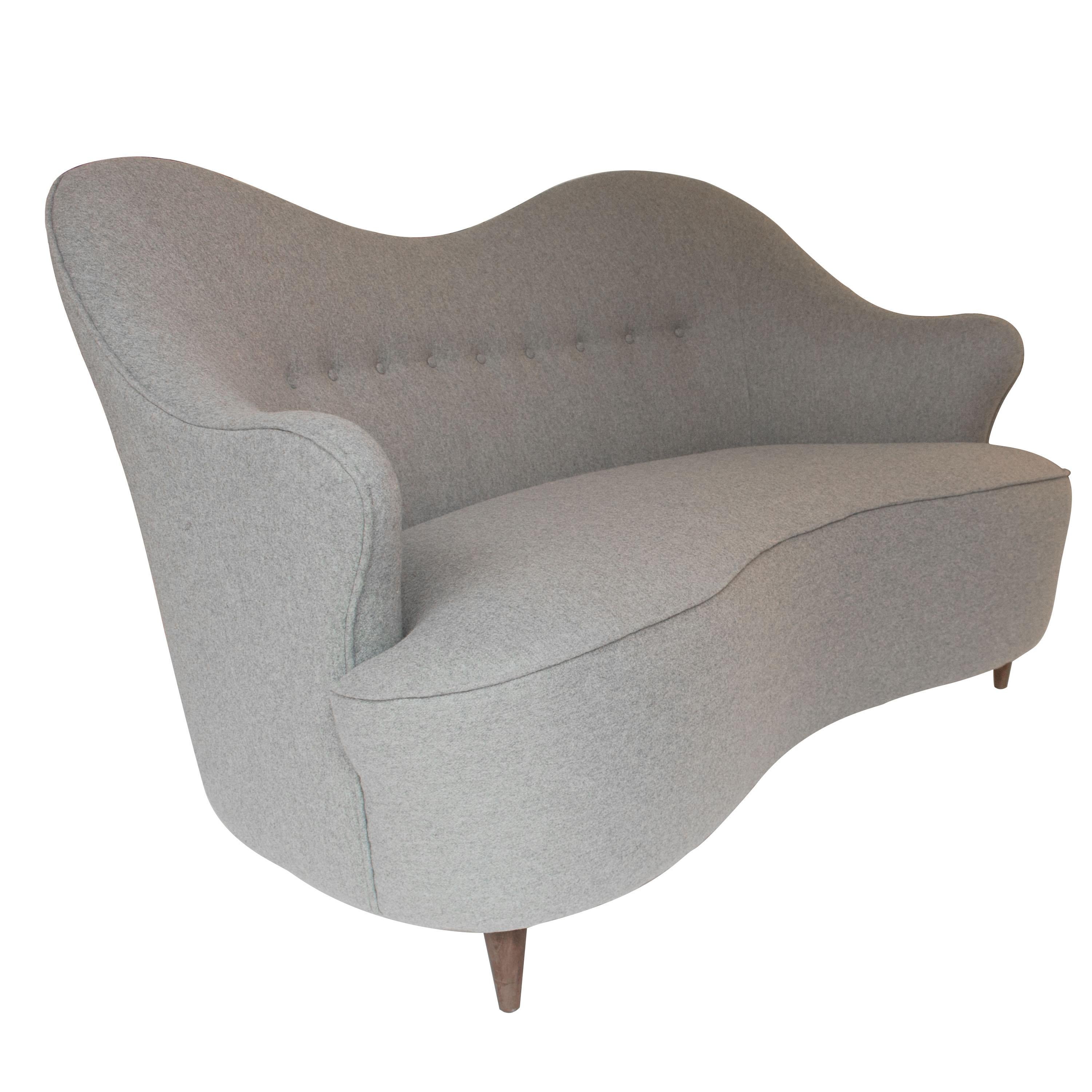 Zweisitziges Sofa, das Finn Juhls zugeschrieben wird und in den 50er Jahren in Italien hergestellt wurde. 
Gefertigt aus Massivholz und mit grauem Wollfilz gepolstert. Klassische konische Beine aus Teakholz.