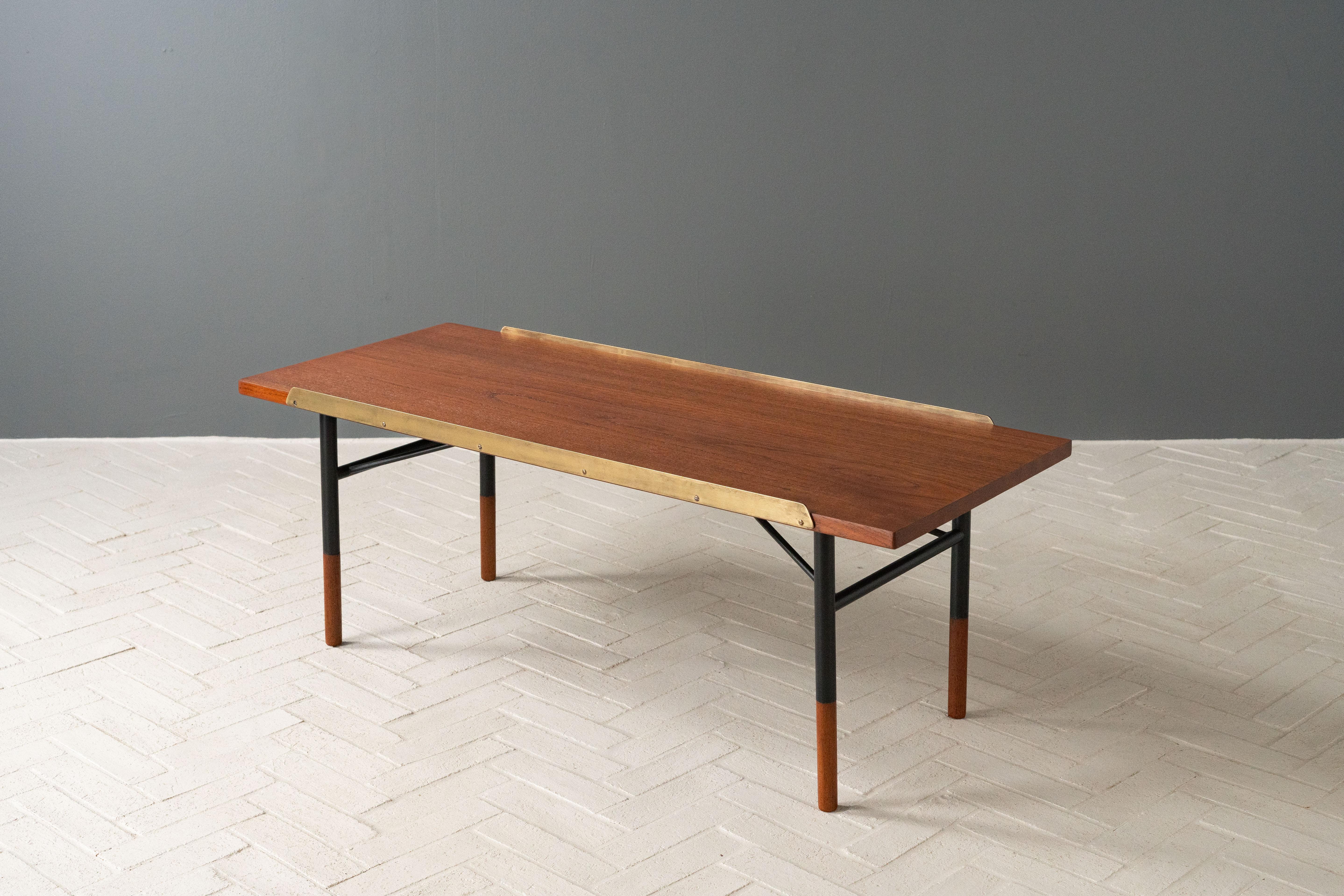 Denmark, ca. 1950s. A scarce and early coffee table or bench by Finn Juhl for Bovirke. Referred to as the Table Bench, it features a light and elegant design with a rectangular teak top supported by a tubular black enameled steel frame. Stylish